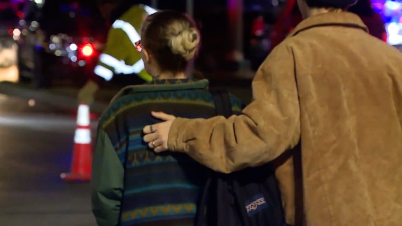 Man places hand on woman's back as police investigate mass shooting at MSU 2.13.23