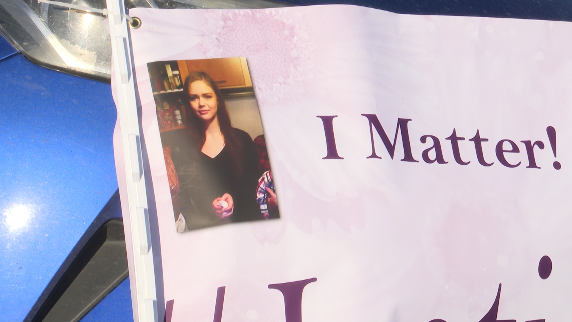 A corner of a sign from the vigil featuring a photo of Kassi