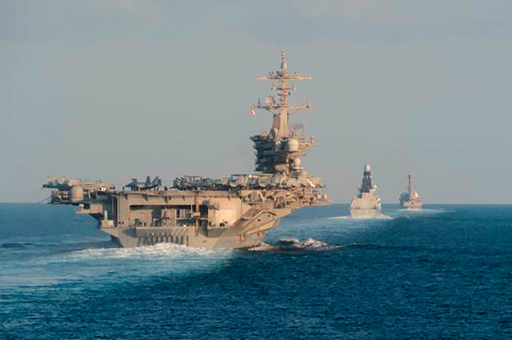 In this Nov. 19, 2019, photo made available by U.S. Navy, the aircraft carrier USS Abraham Lincoln, left, the air-defense destroyer HMS Defender and the guided-missile destroyer USS Farragut transit the Strait of Hormuz with the guided-missile cruiser USS Leyte Gulf. 