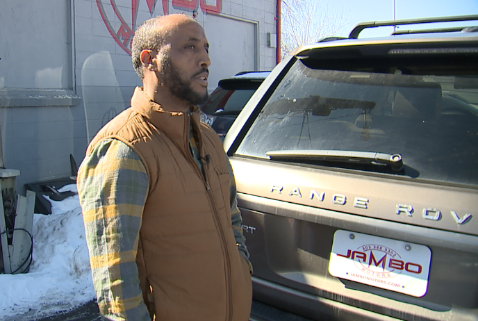 Jambo Woldyohannis stands in front of a Range Rover that has a catalytic converter stolen