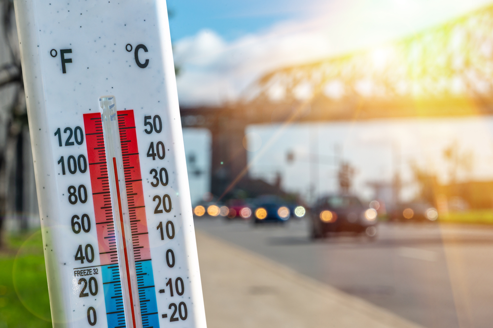 Thermometer in front of cars and traffic during heatwave 