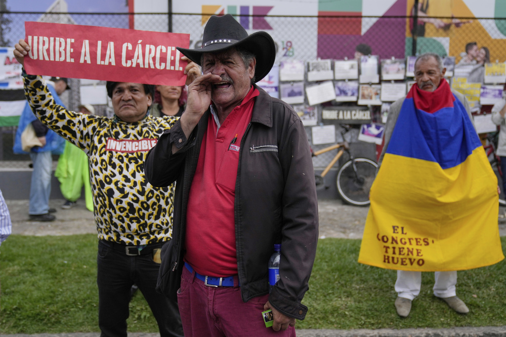 Opponents of former President Alvaro Uribe gather outside the court where a verdict is expected in his trial for witness tampering in Bogota, Colombia.