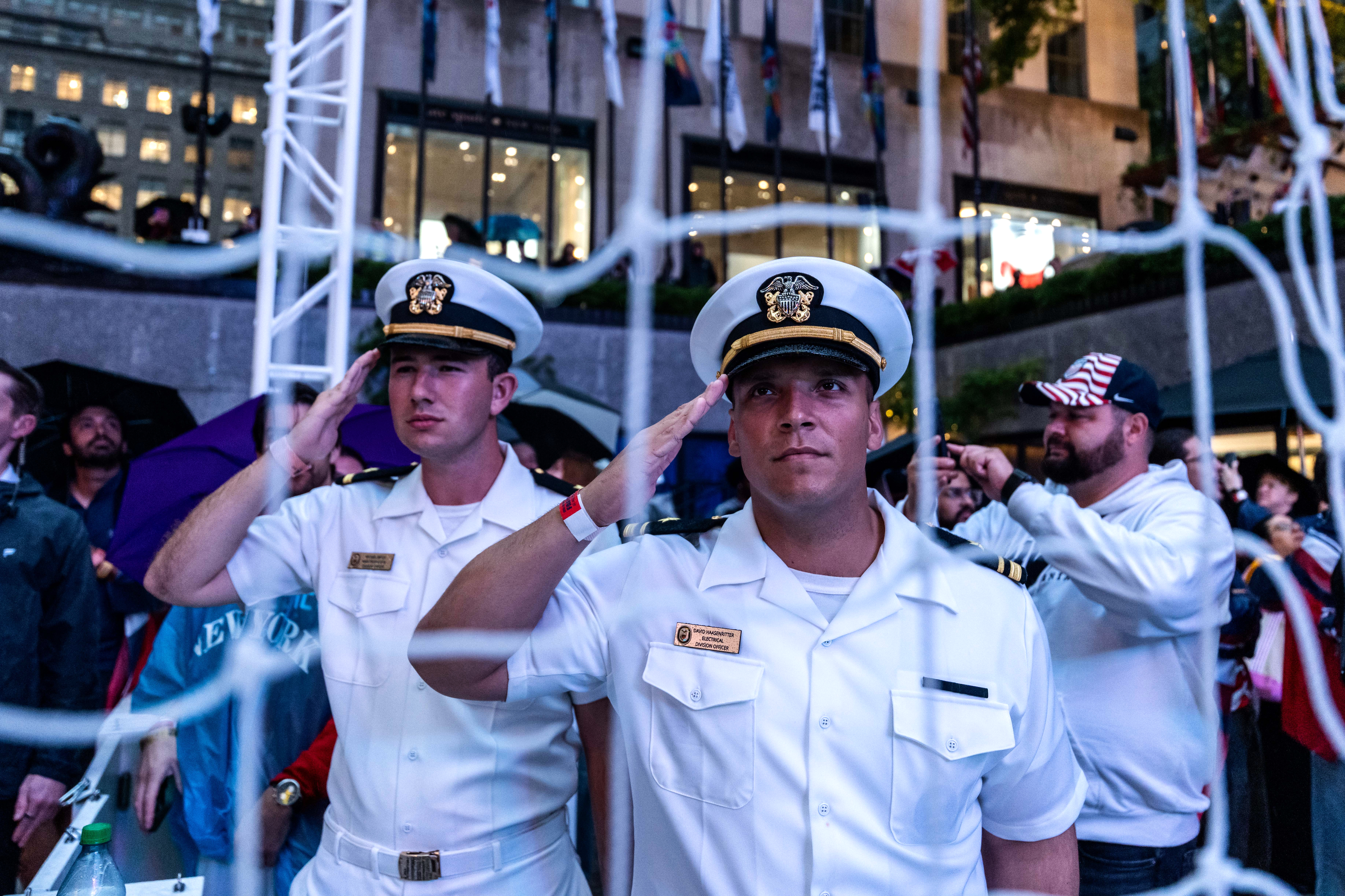United States Navy personnel salute during the national anthem at a watch party in a fan village in New York's Rockefeller Center for a World Cup round of 16 soccer match between the United States and Belgium, Monday, July 6, 2026 in New York.