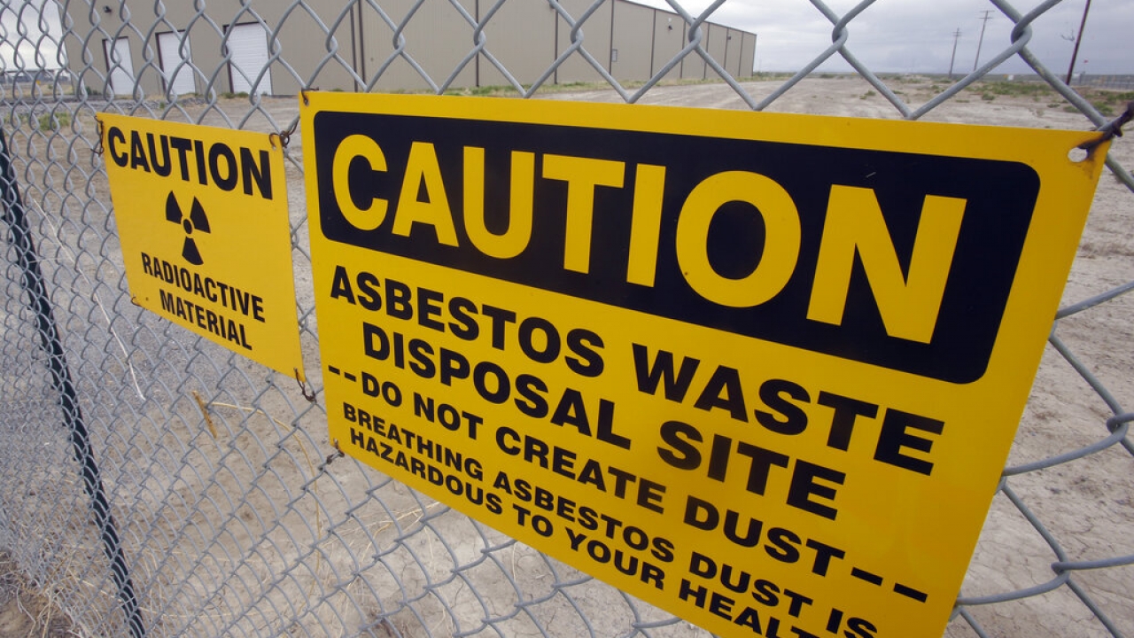 An asbestos waste caution sign hangs on a fence in front of a building that houses depleted uranium in Utah.