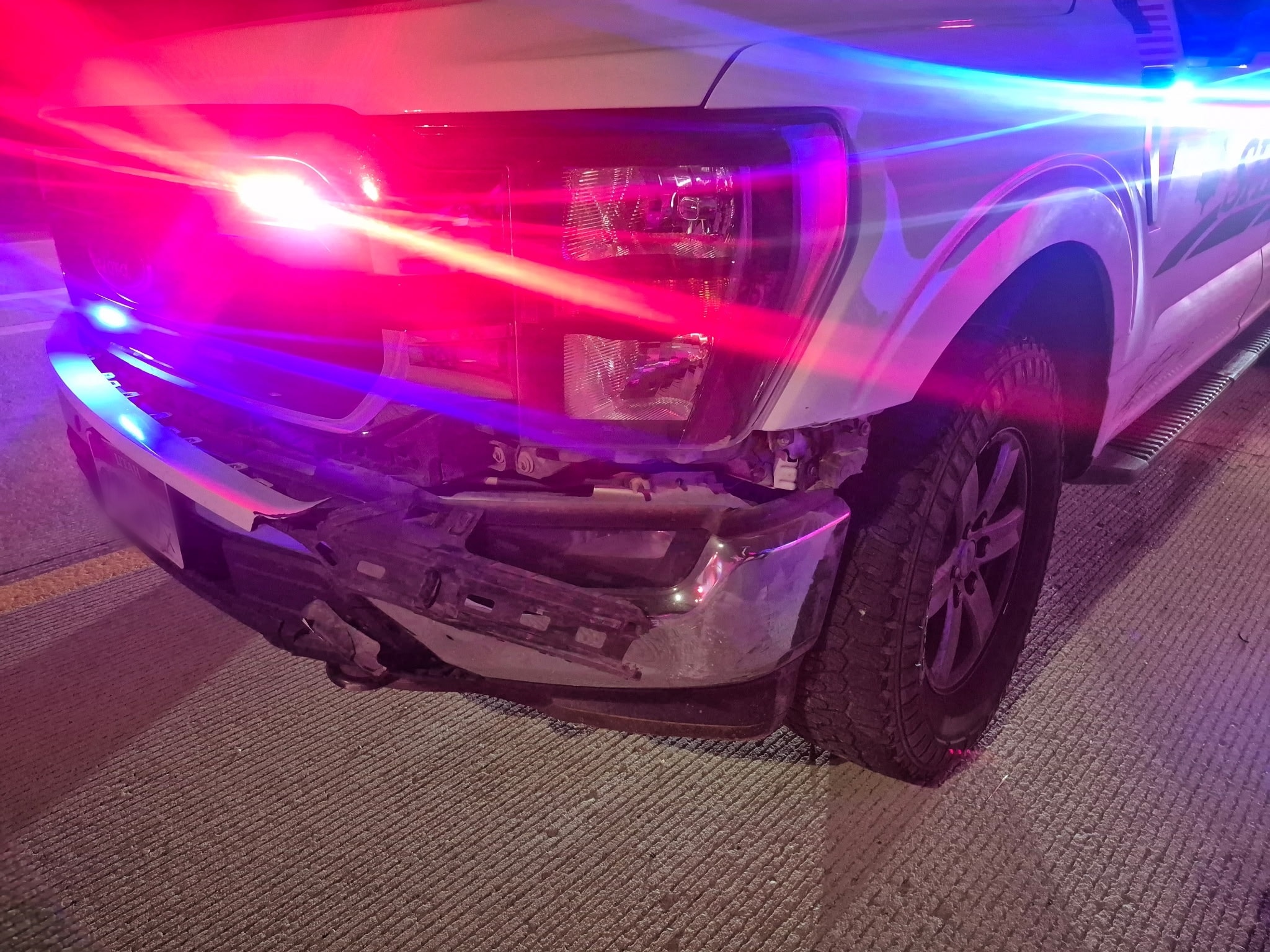 A photo from the scene released by the Utah County Sheriff's Office. It's night, and the front of the police cruiser is dented from the impact.