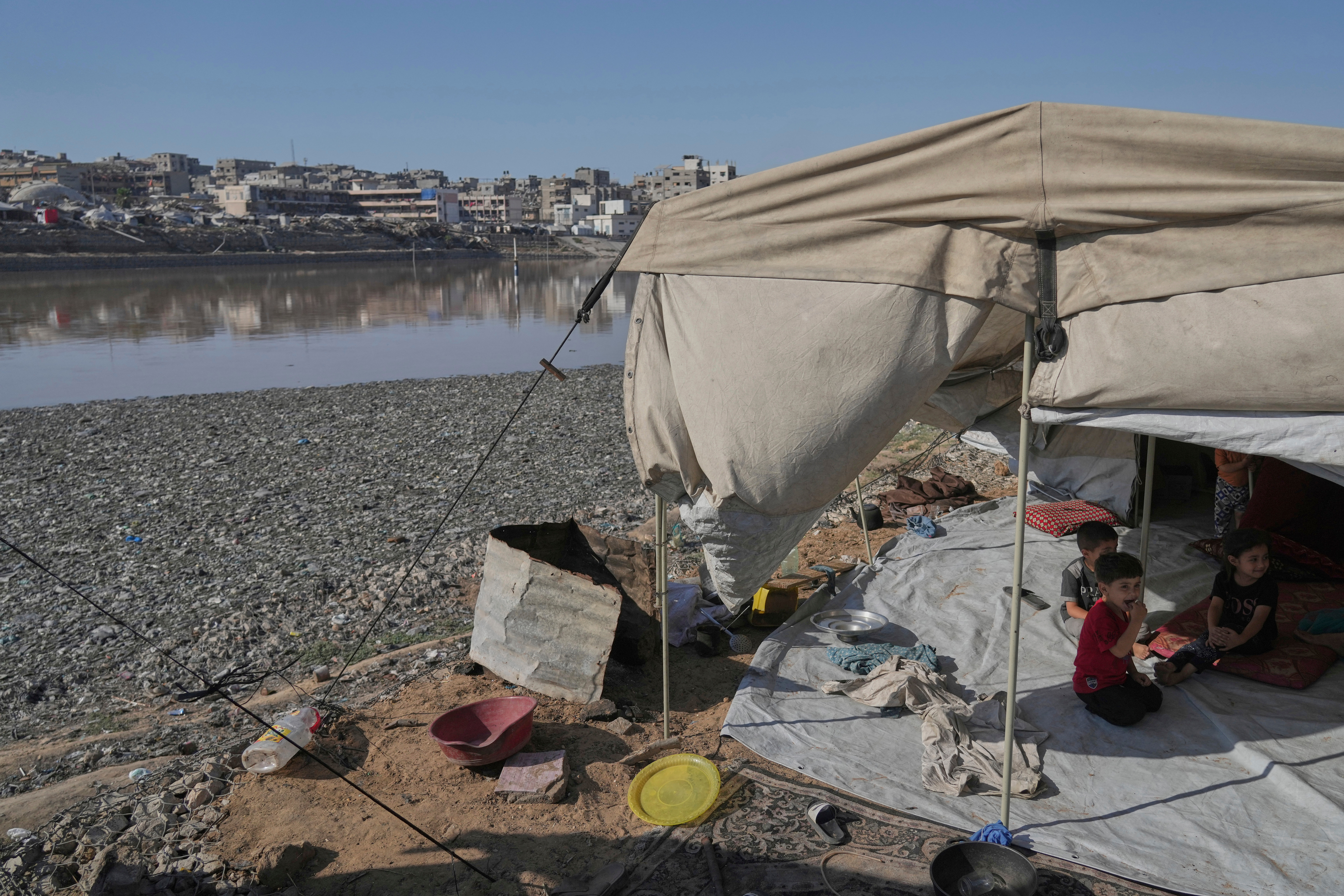 Children sit in their tent at a camp for displaced Palestinians, located near a rainwater collection reservoir that has been contaminated by sewage and garbage following the Israeli air and ground operations in Gaza City, Friday, July 18, 2025. 