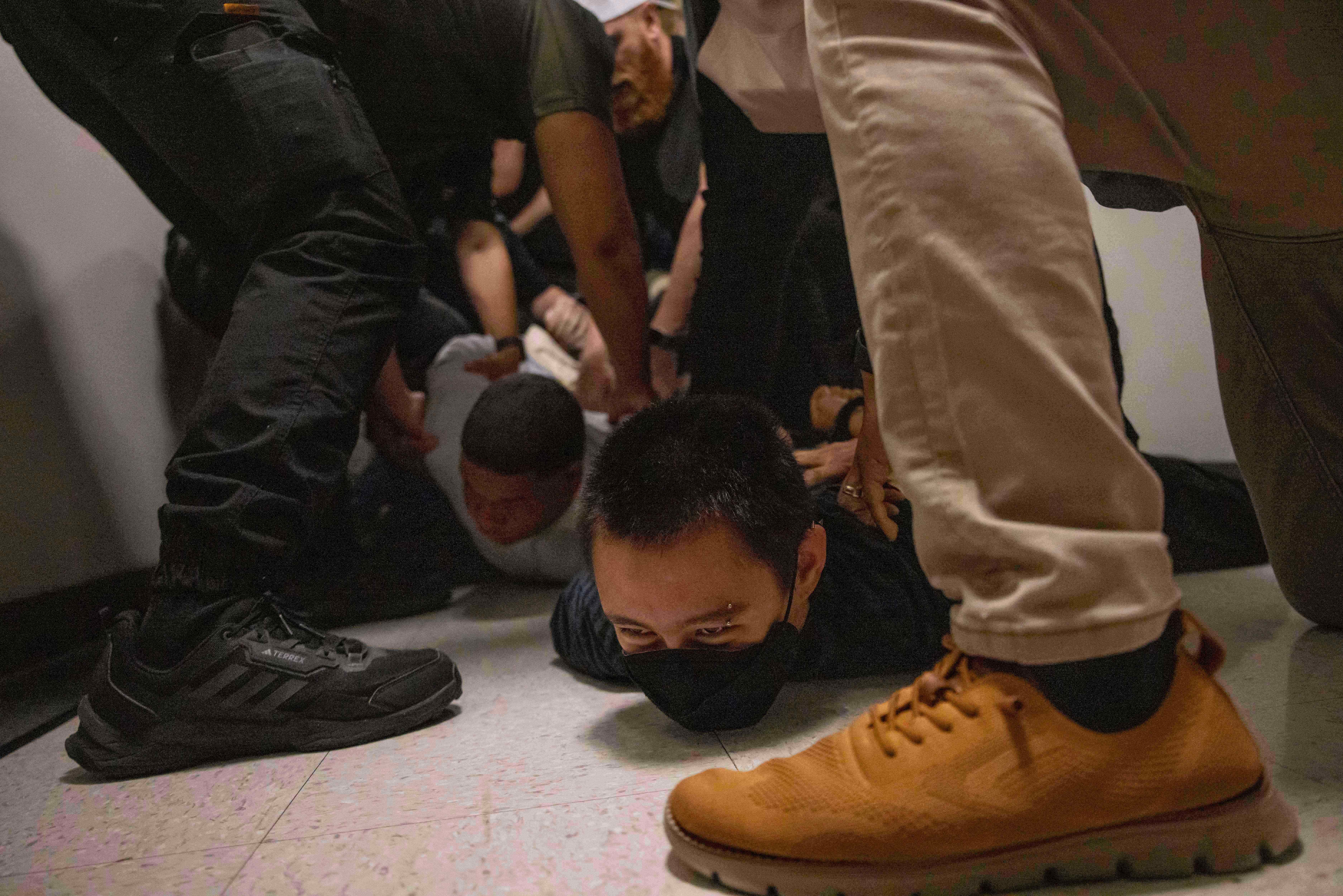 A Dominican man, left, and an activist, right, are detained by plainclothes officers with Immigration and Customs Enforcement