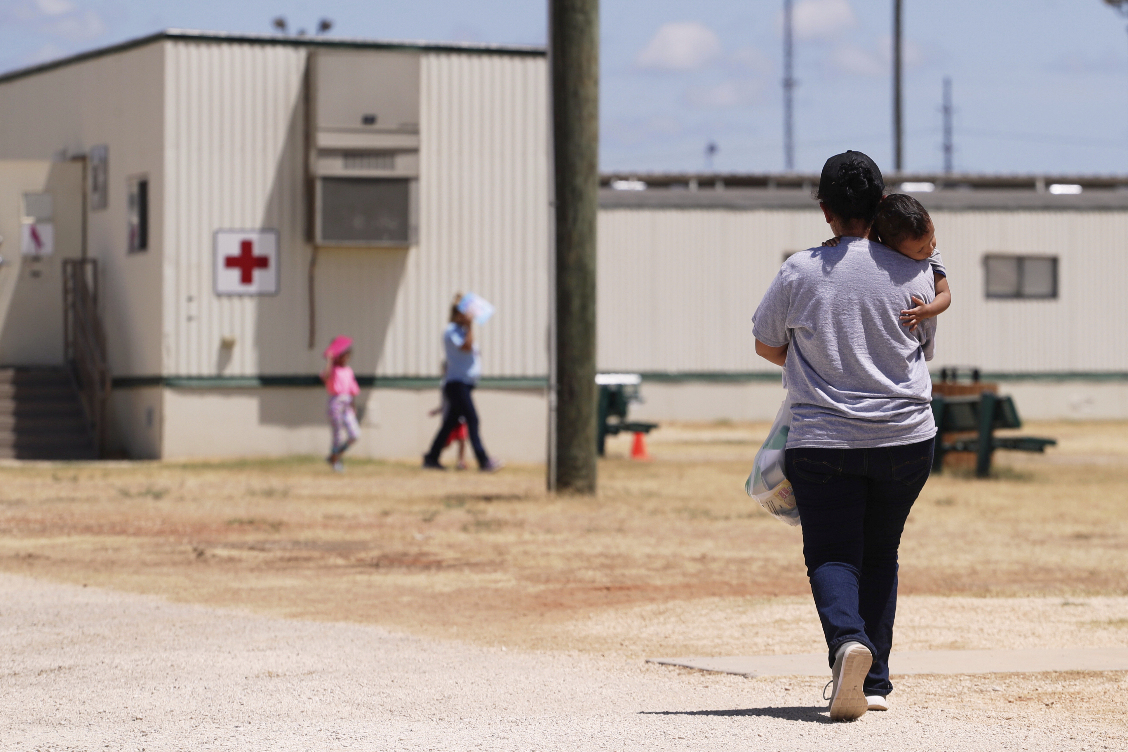 FILE - Immigrants seeking asylum walk through the ICE South Texas Family Residential Center in Dilley, Texas.