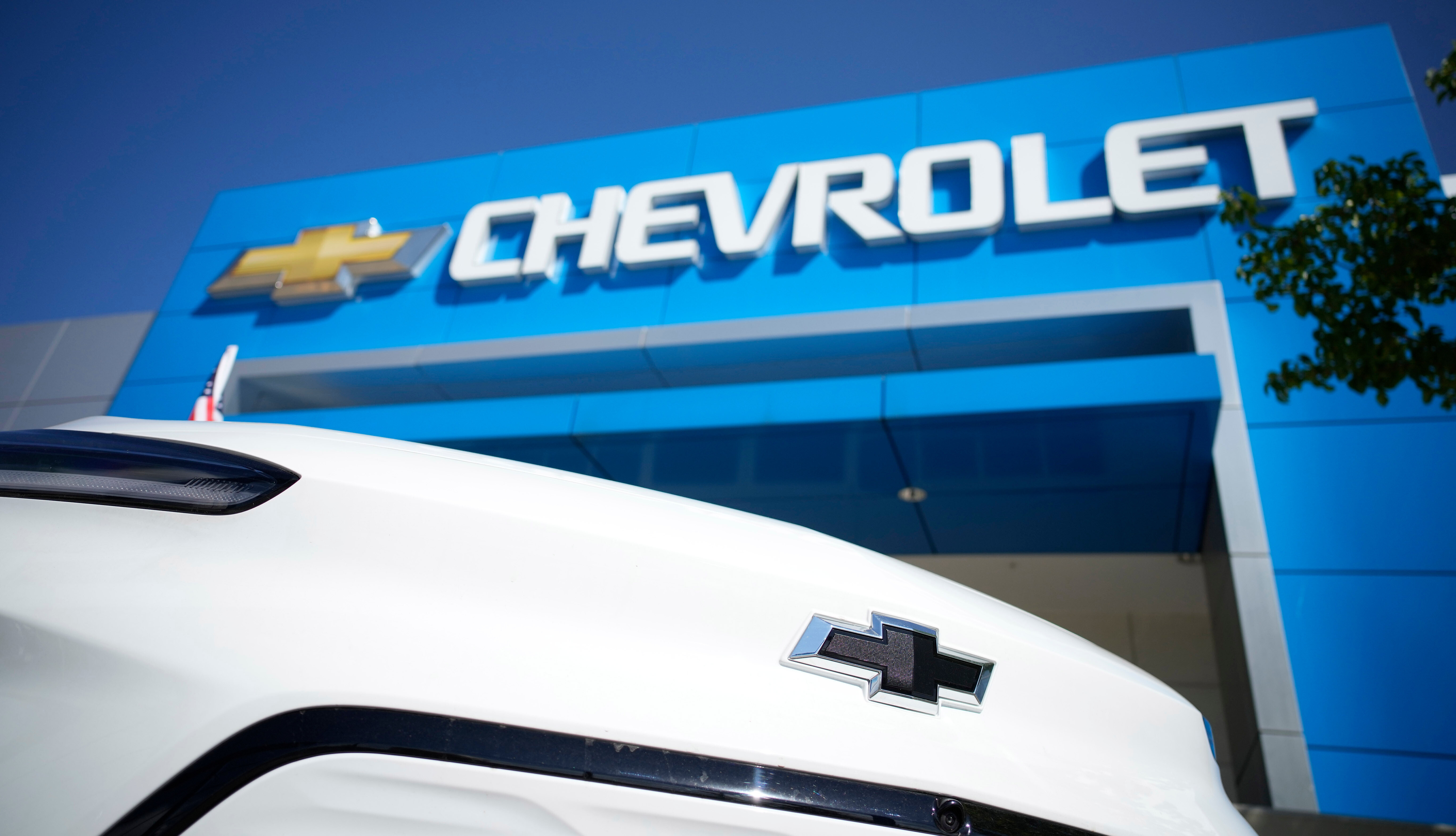 The company logo shines off the nose of an unsold 2022 Bolt electric vehicle on display in front of a Chevrolet dealership Sunday, Sept. 12, 2021, in Englewood, Colo.  