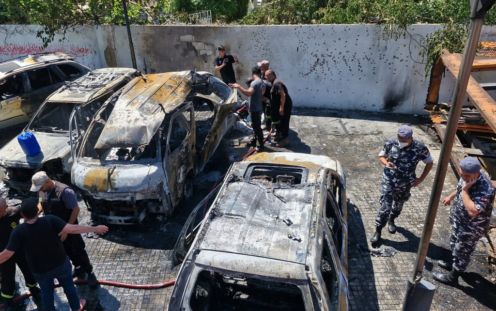 Lebanese police officers, right, and Civil Defence workers check the site were an Israeli airstrike attacked a car in the southern port city of Sidon, Lebanon, Wednesday, June 10, 2026.