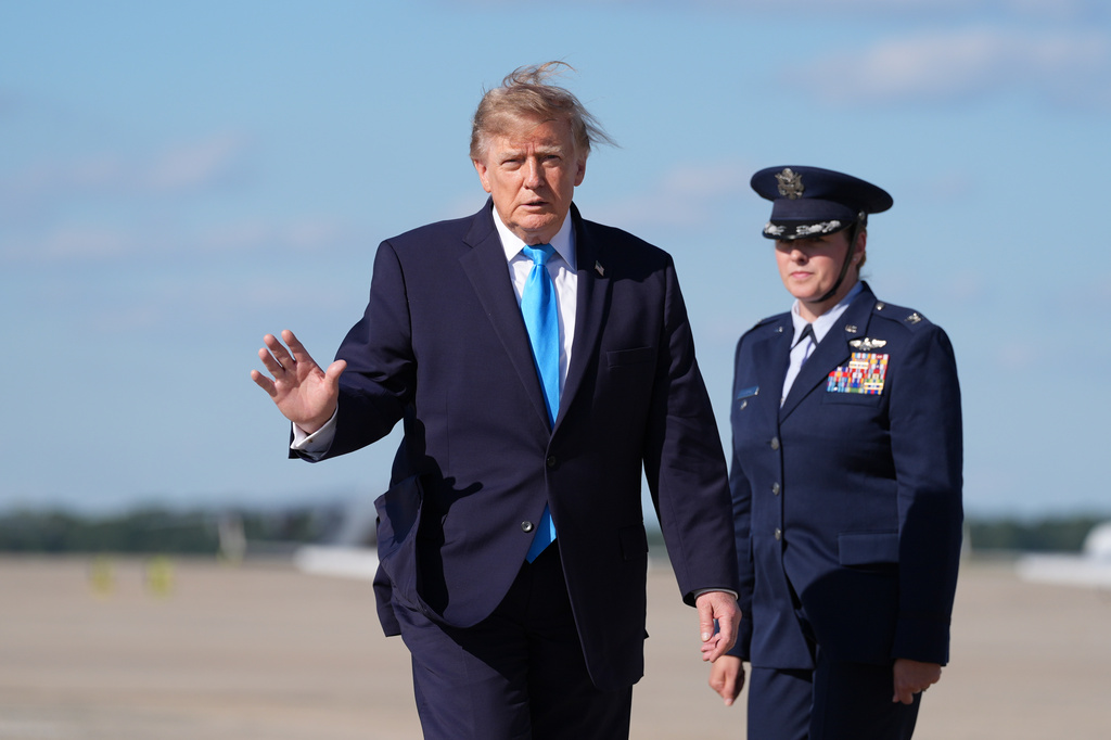President Donald Trump walks to board Air Force One, Monday, Oct. 5, 2026, at Joint Base Andrews, Md., escorted by Air Force 89th Air Wing Deputy Commander Melissa Dombrock.