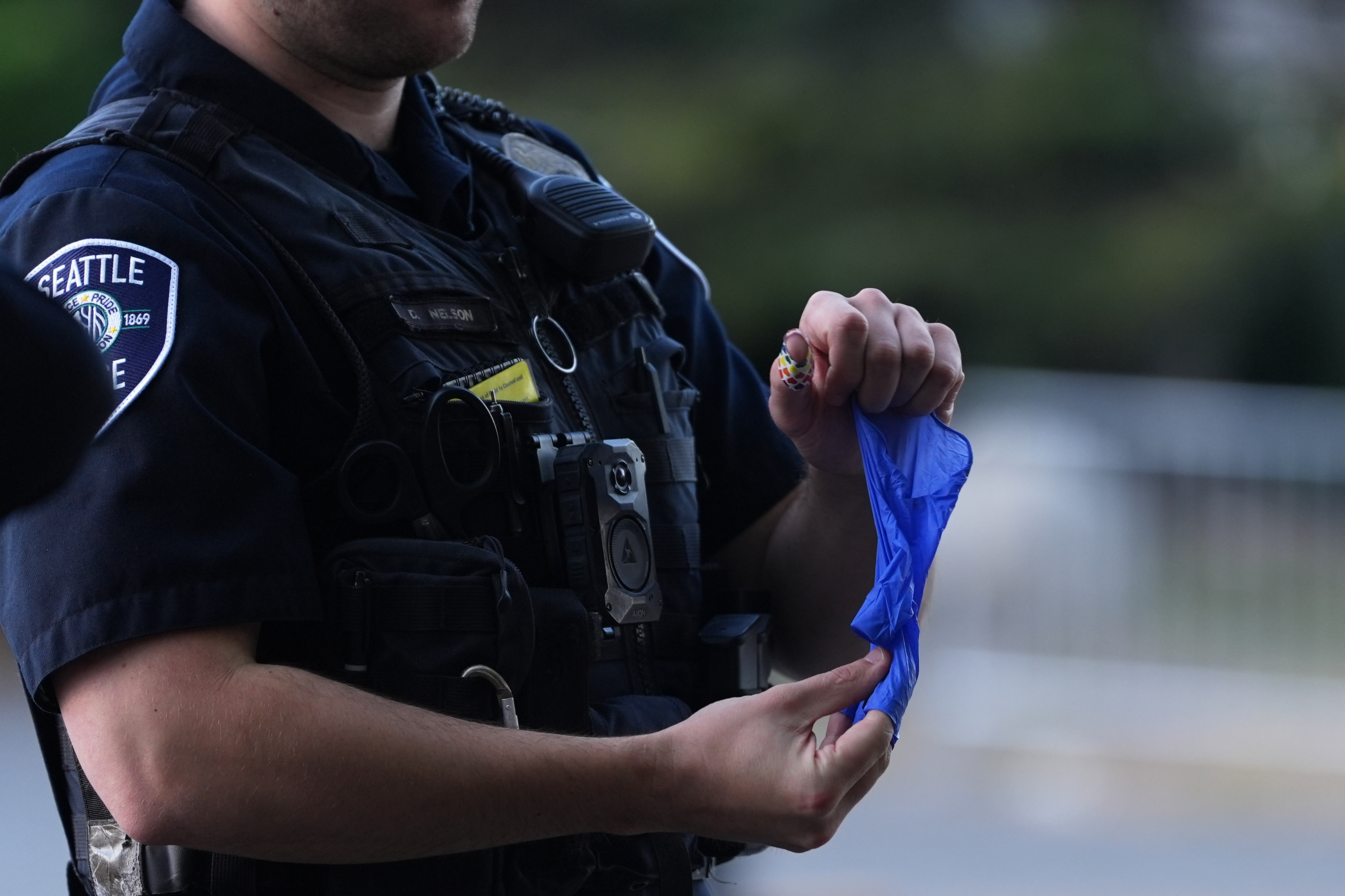 A police officer puts a bullet casing into a rubber glove after he received it from a person who found it, following a shooting at Seattle Center during the Bite of Seattle food festival, Monday, July 27, 2026, in Seattle. 