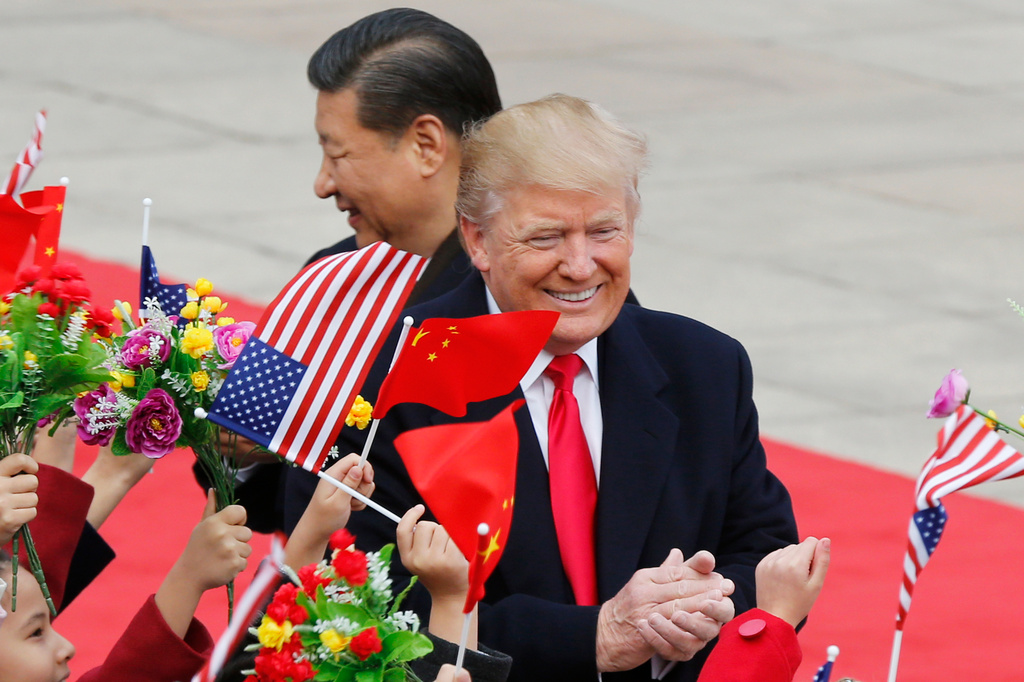 FILE - U.S. President Donald Trump, right, and Chinese President Xi Jinping are greeted by children waving flowers and flags during a welcome ceremony at the Great Hall of the People in Beijing, Nov. 9, 2017.