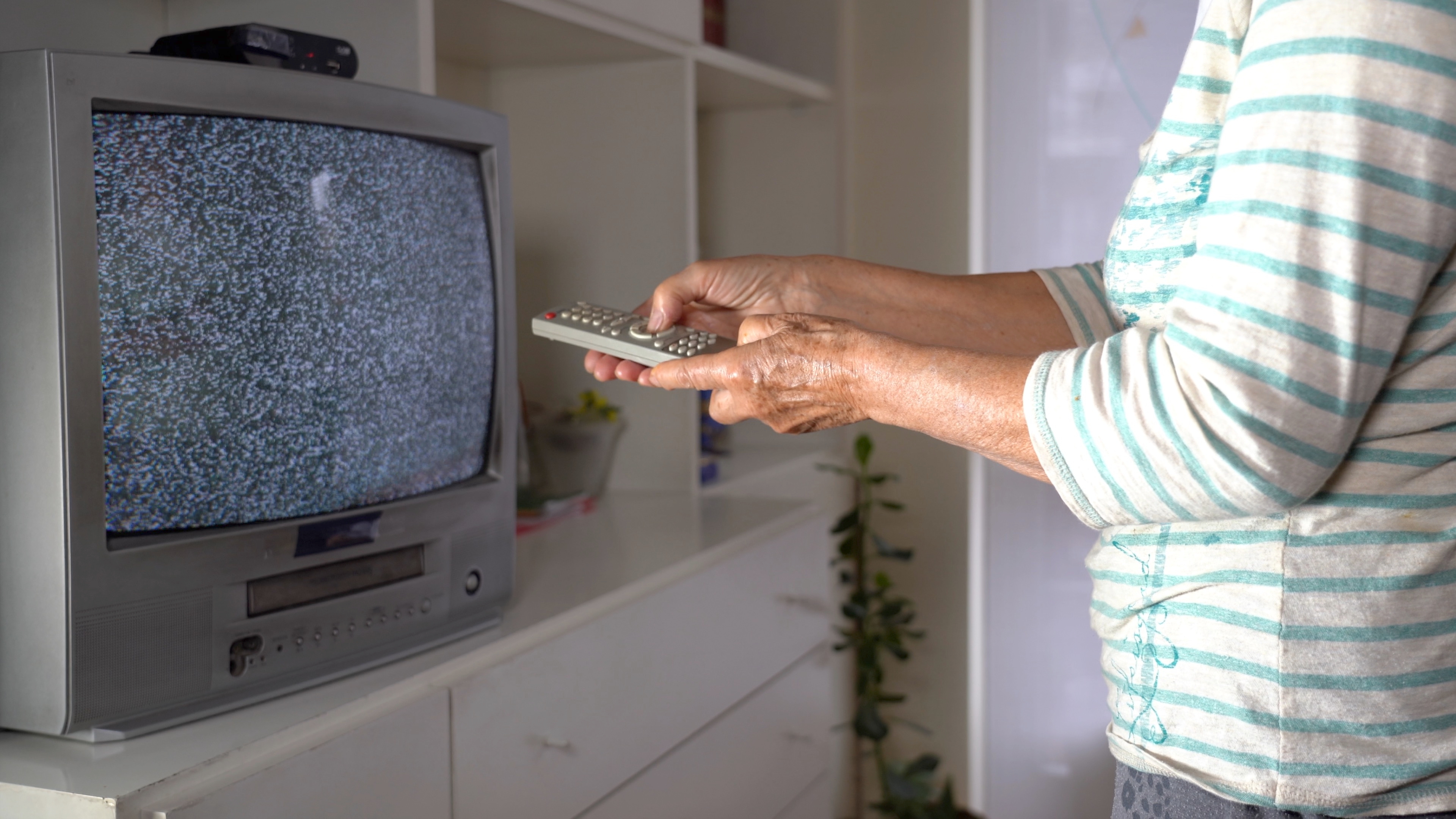 A woman points a remote at a TV.