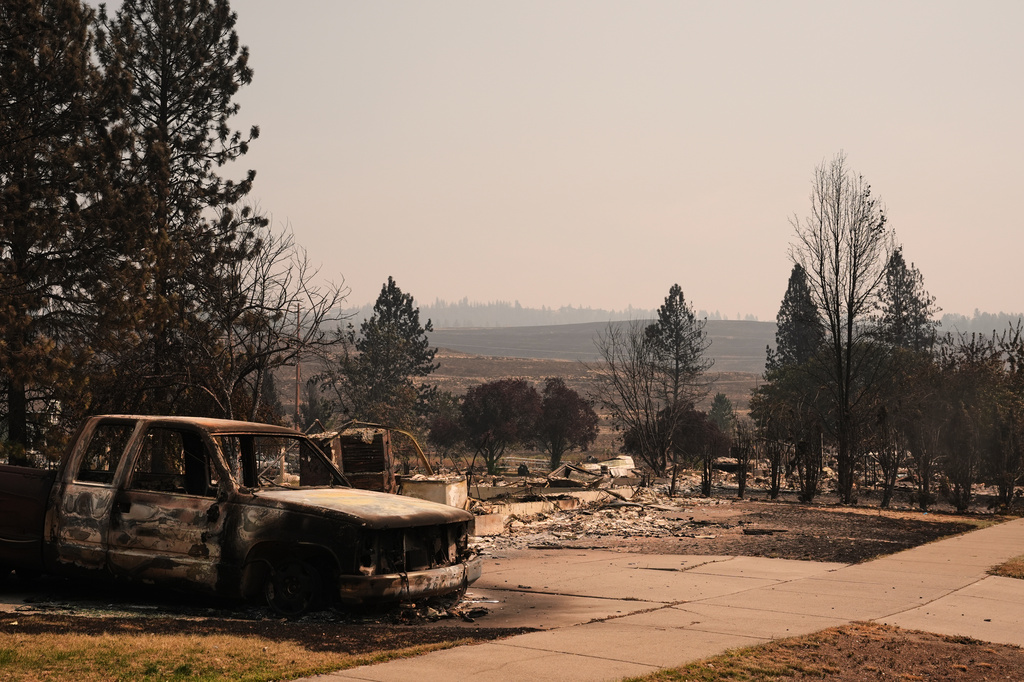 A burned truck sits in a driveway near several destroyed homes in a residential neighborhood Tuesday, Aug. 4, 2026, after a wildfire hit the northern part of Spokane, Wash.