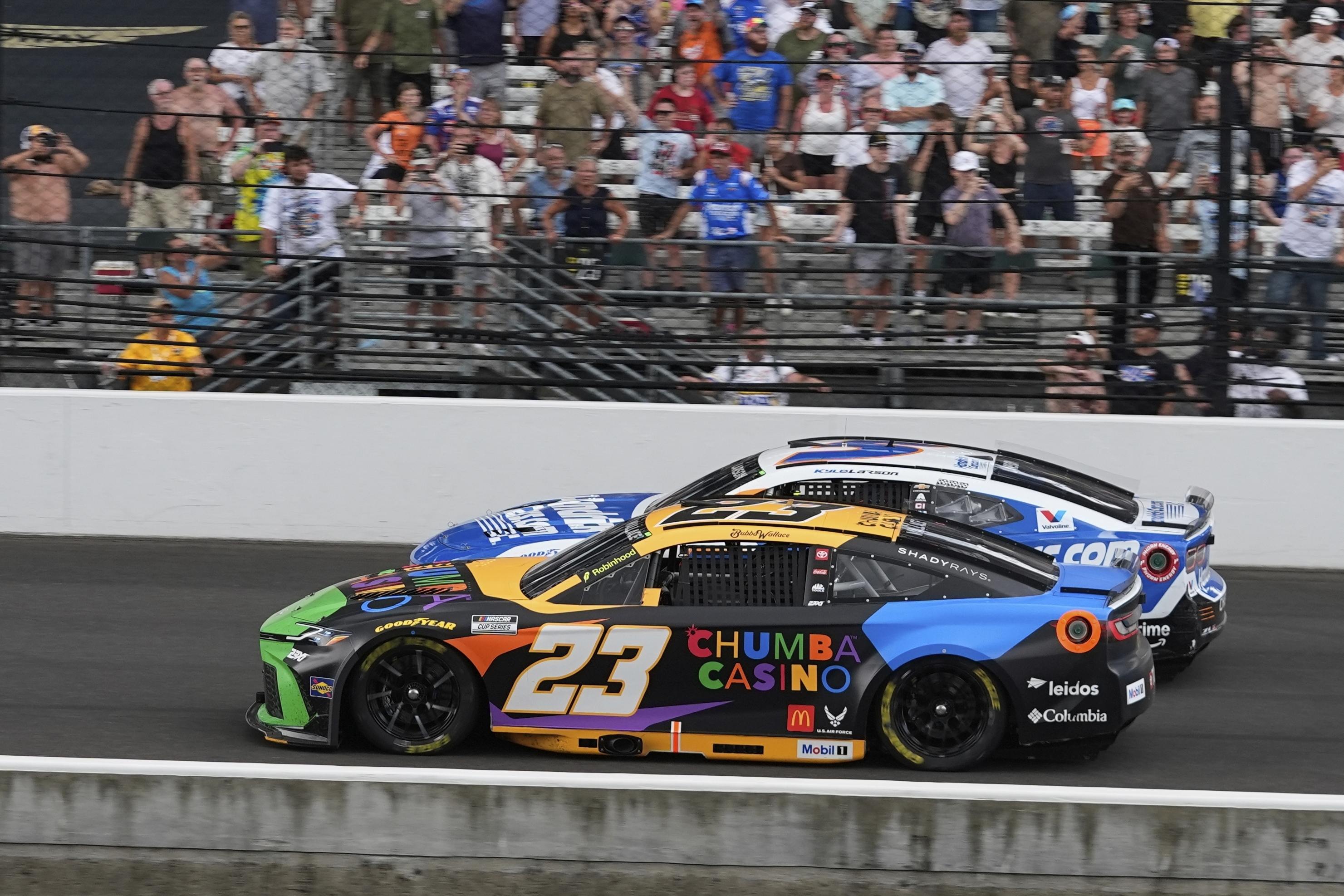 Bubba Wallace (23) leads Kyle Larson restart during a NASCAR Cup Series auto race at Indianapolis Motor Speedway, Sunday, July 27, 2025, in Indianapolis.