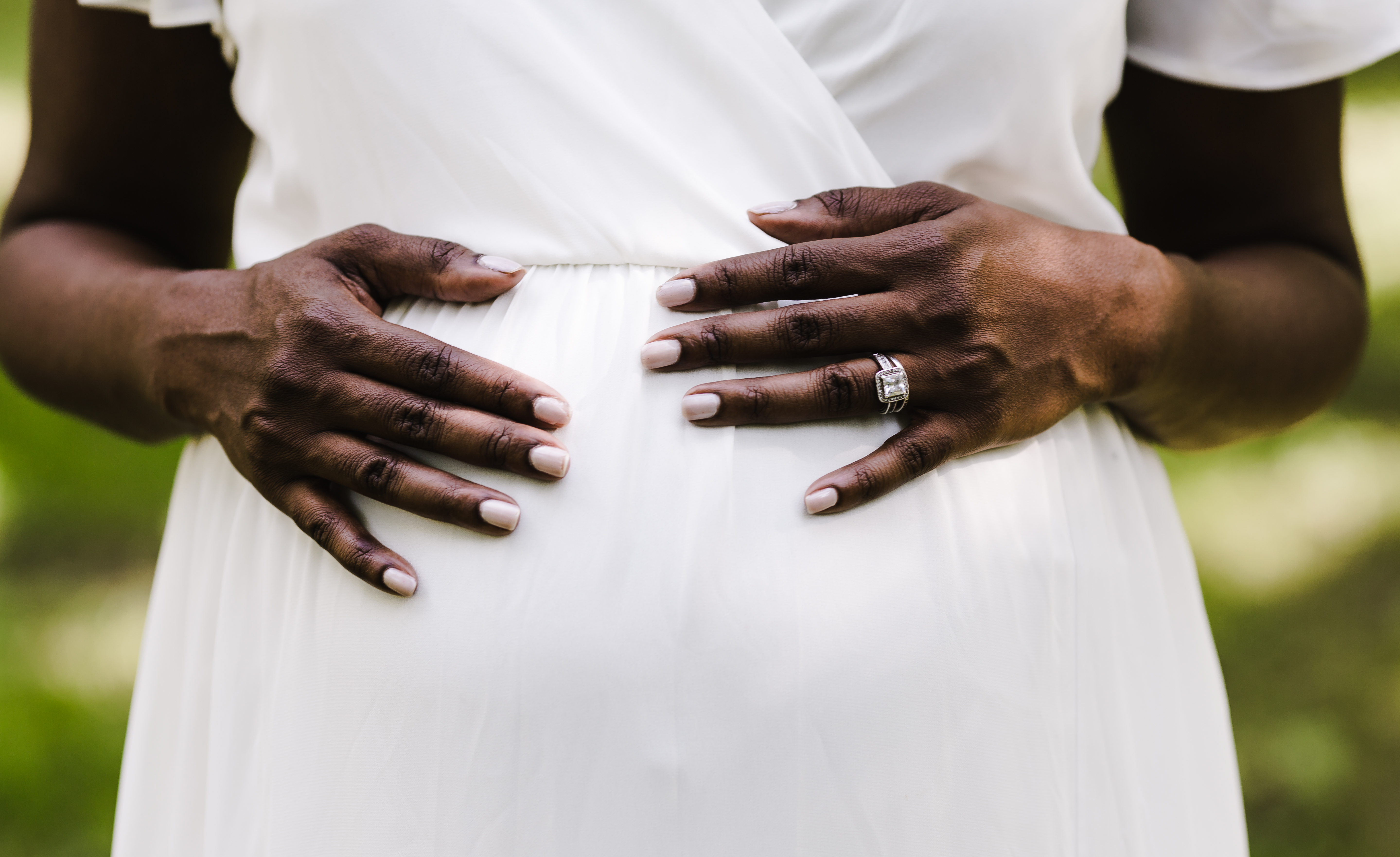 woman-in-a-white-dress-holds-pregnant-belly-SBI-346271138.jpg