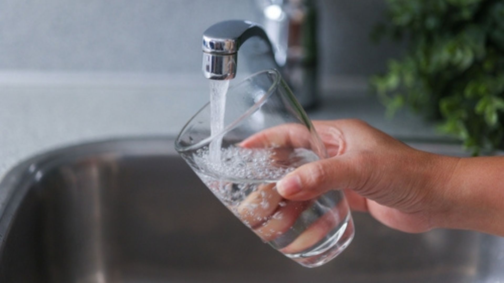 Stock image of a person filling a glass with tap water.