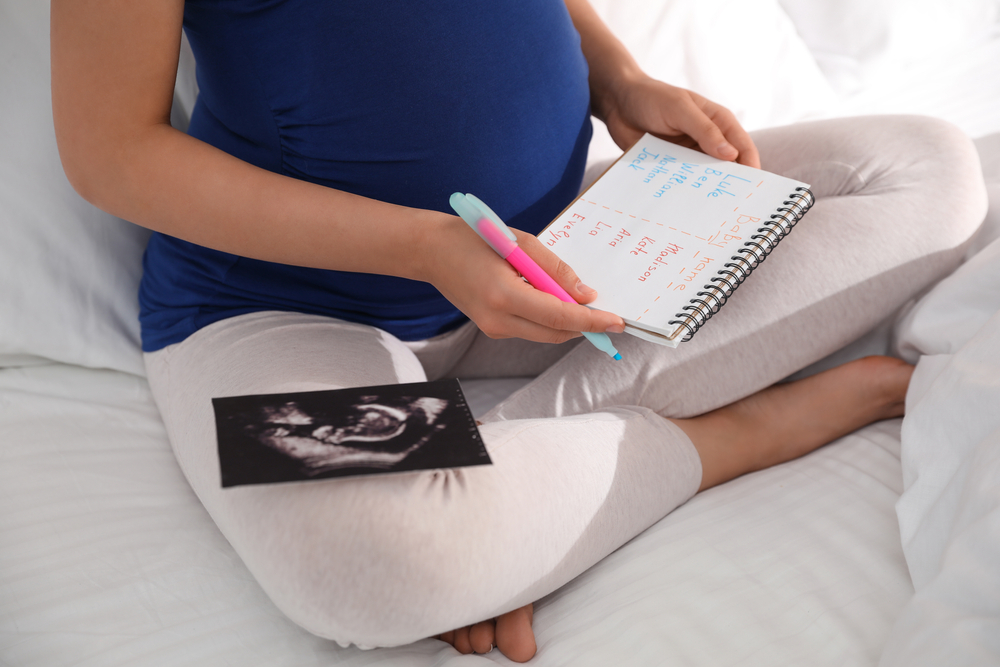 Pregnant,Woman,With,Baby,Names,List,And,Sonogram,Sitting,On