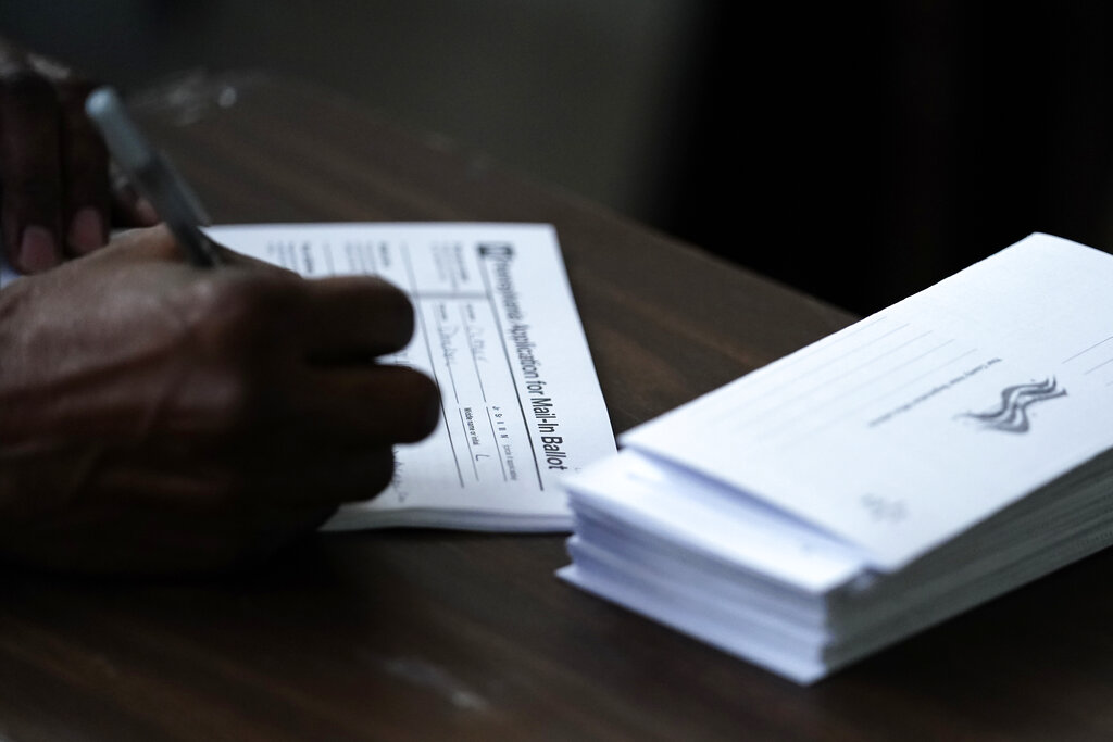 FILE - In this Sept. 29, 2020, file photo Philadelphia City Council President Darrell L. Clarke fills out an application for a mail-in ballot before voting at the opening of a satellite election office at Temple University's Liacouras Center in Philadelphia.