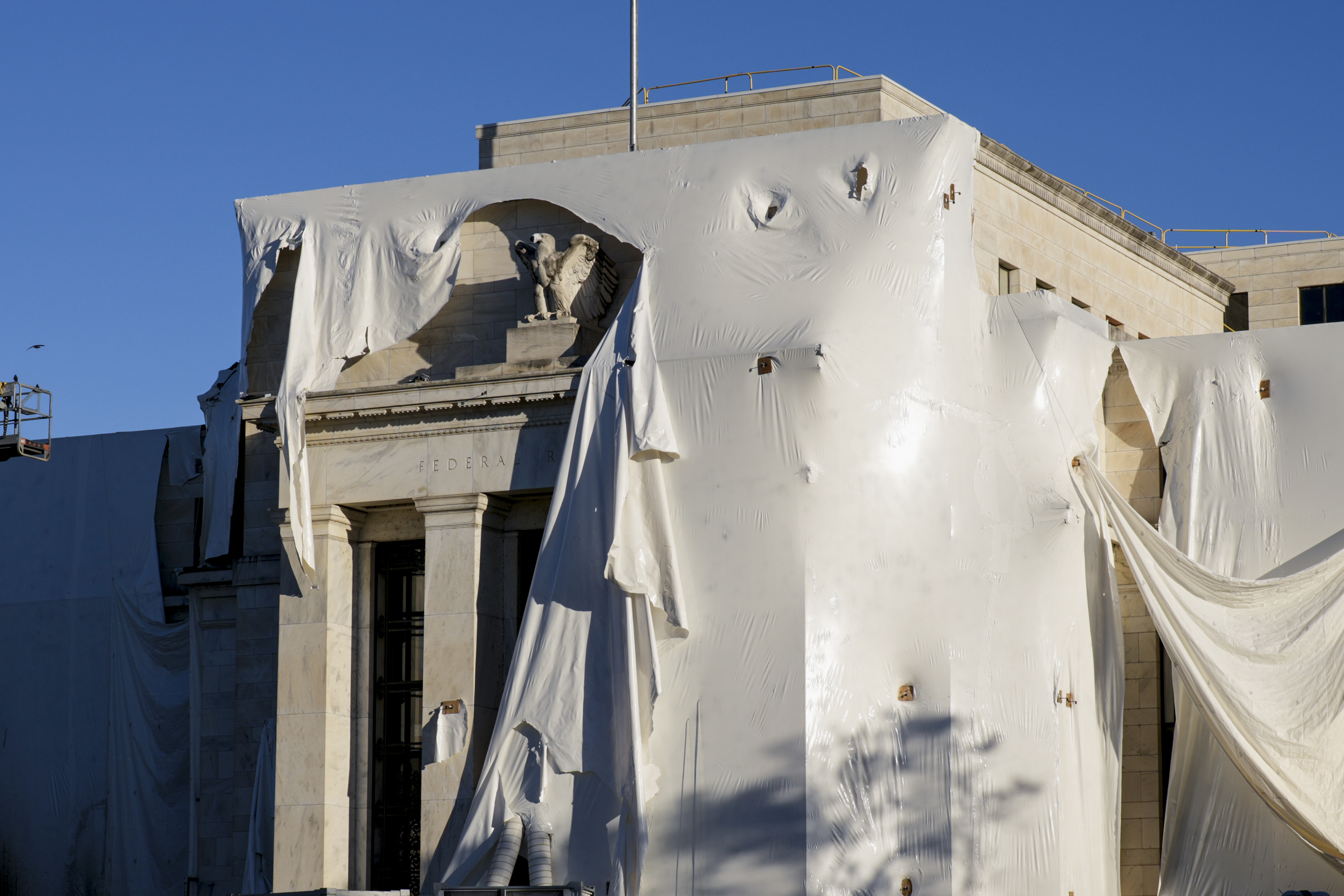  The sculpture of an eagle looks out from behind protective construction wrapping on the facade as the Federal Reserve Board Building undergoes both interior and exterior renovations, in Washington, Monday, Oct. 23, 2023. 