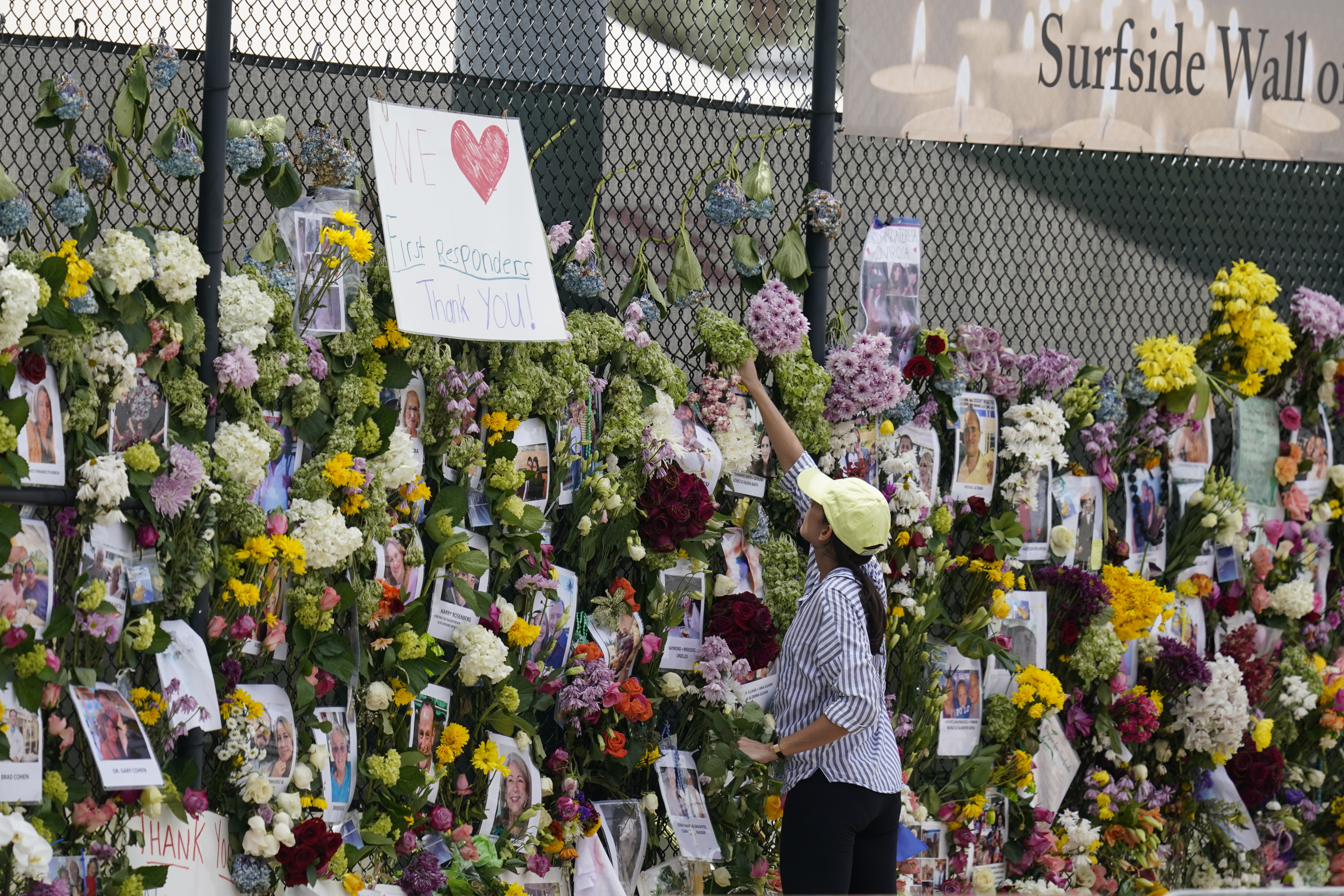 Volunteer replaces flowers at Surfside Wall of Hope & Memorial, July 1, 2021