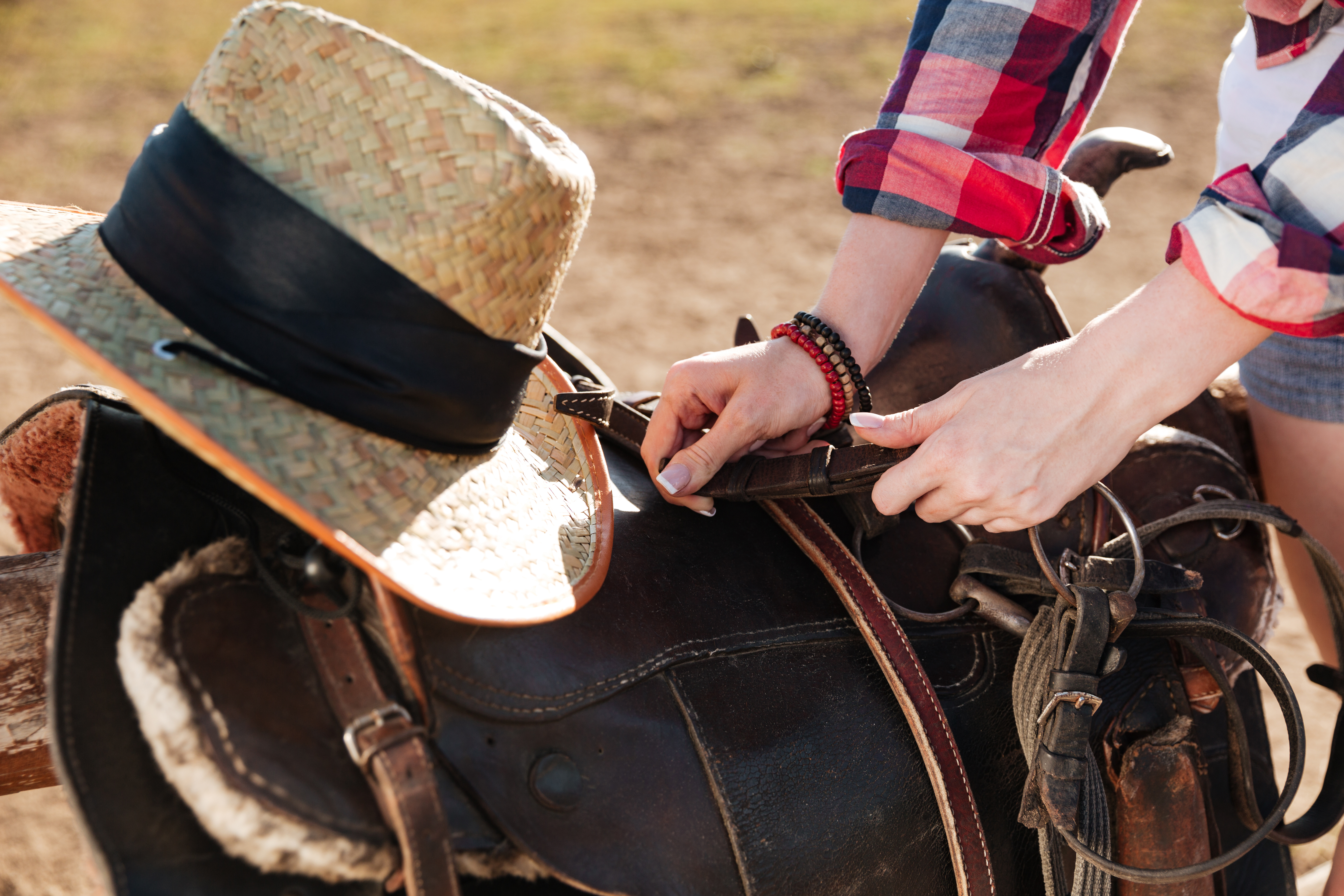 Saddle prepared for horse riding by young woman cowgirl