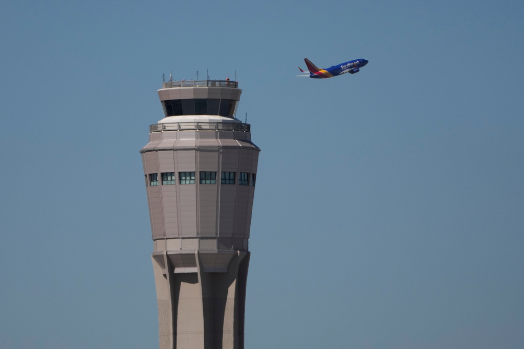 A plane takes off near the air traffic control tower at Harry Reid International Airport, Tuesday, Oct. 7, 2025, in Las Vegas.
