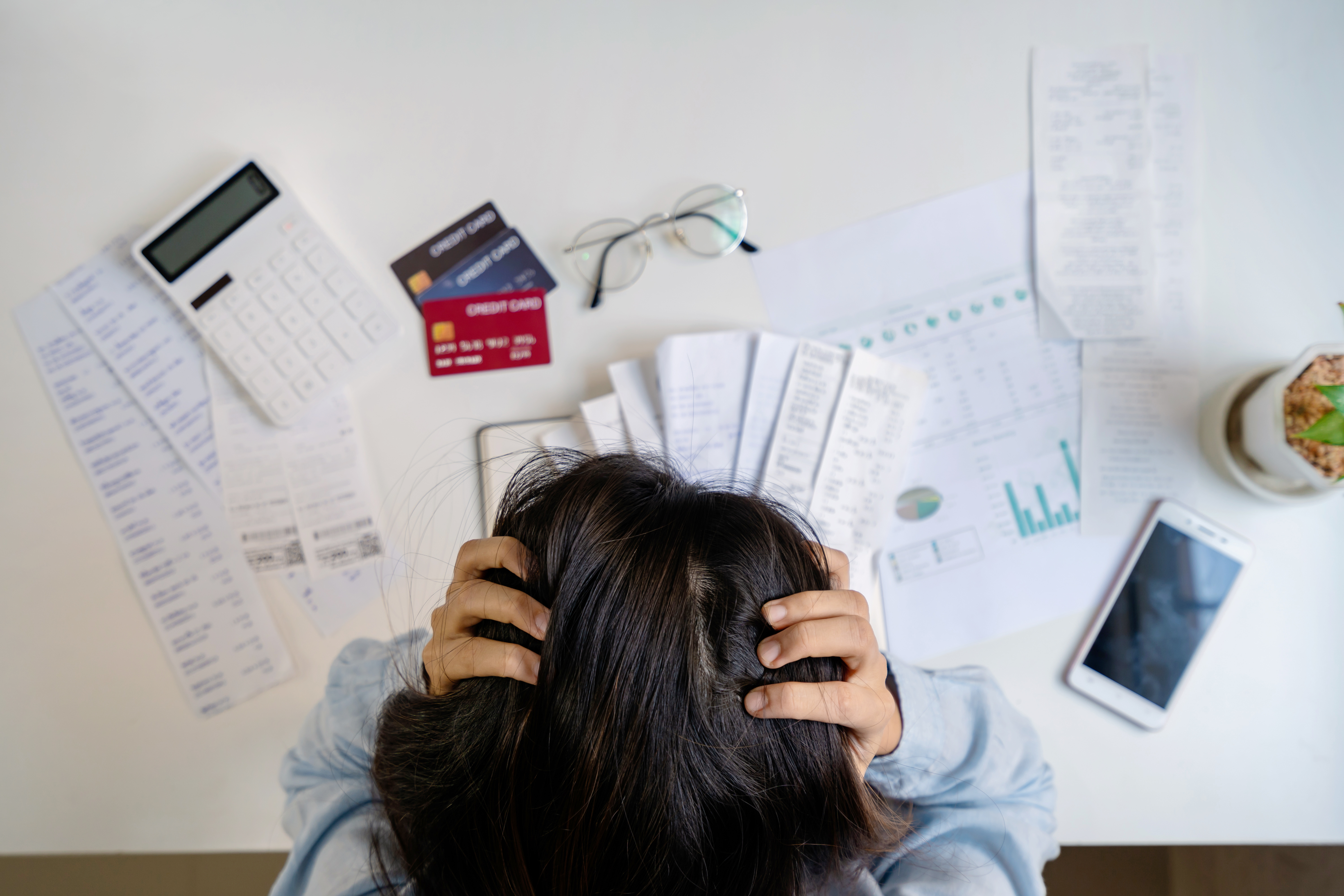 A young woman appearing stressed while looking at bills. 