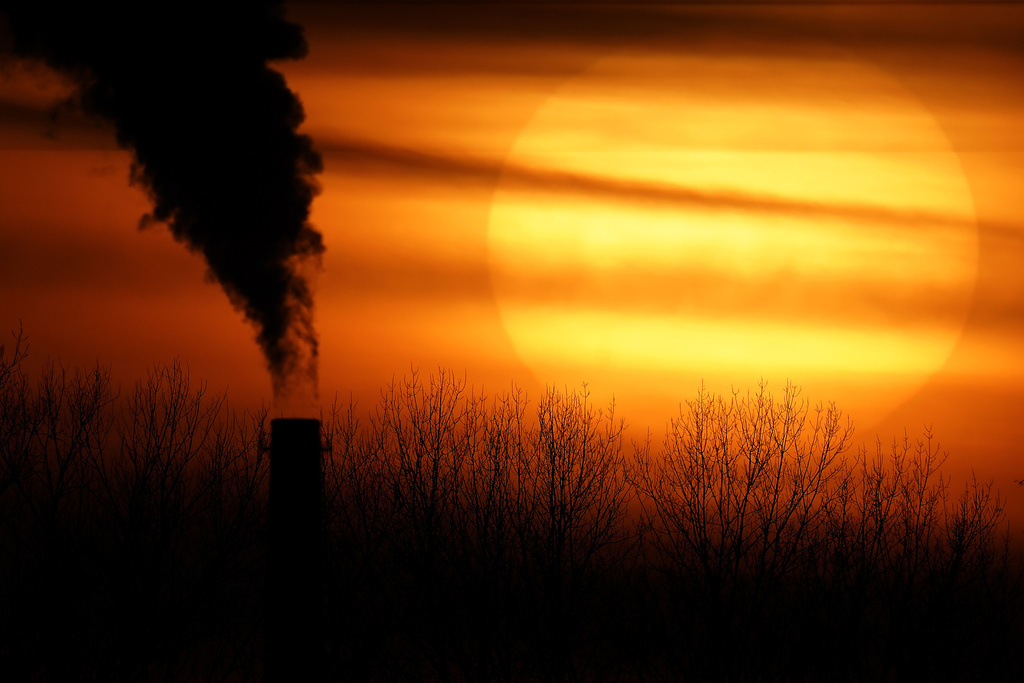 Emissions from a coal-fired power plant are silhouetted against the setting sun in Kansas City, Mo., Feb. 1, 2021.