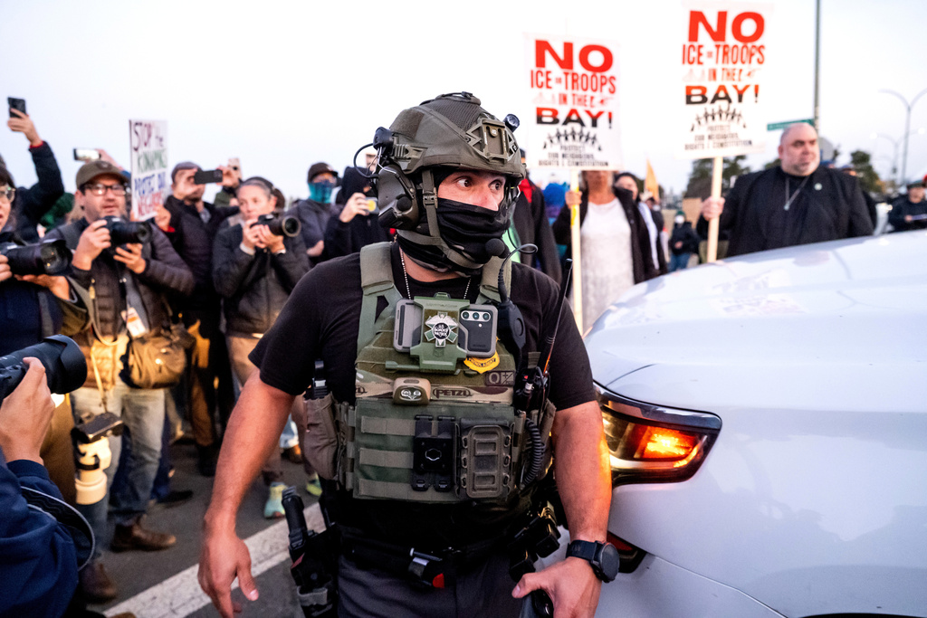 A U.S. Border Patrol officer tries to clear protesters while entering Coast Guard Base Alameda on Thursday, Oct. 23, 2025, in Oakland, Calif. 