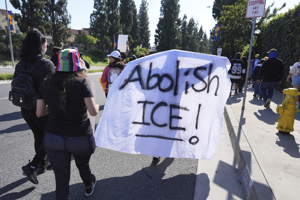 People march along a street during a protest against ICE in Paramount, Calif.