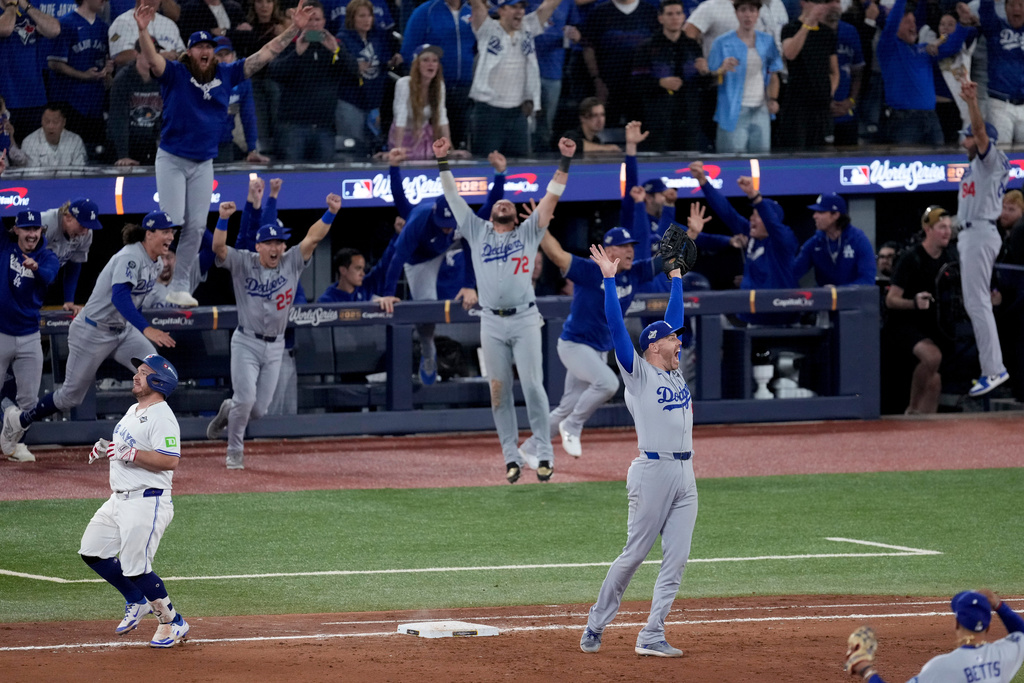 Los Angeles Dodgers' Freddie Freeman, right, and his teammates celebrate their win in Game 7 of baseball's World Series as Toronto Blue Jays' Alejandro Kirk, left, is out at first, Sunday, Nov. 2, 2025, in Toronto.