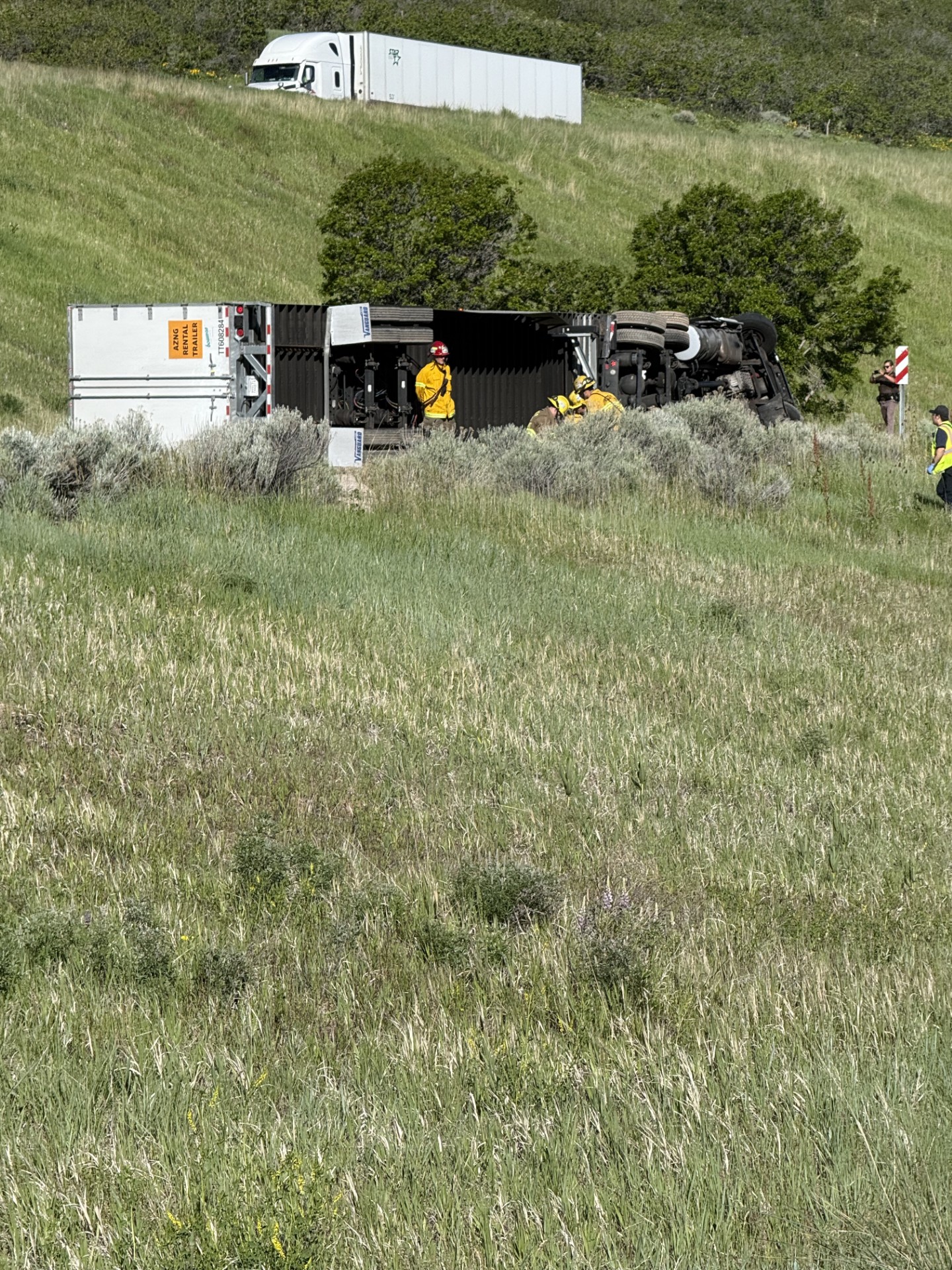 A photo of the crash sent in by FOX 13 viewer Bob Tackleberry. It's day time, the semi trailer lies on its side. A group of firefighters assess the scene.