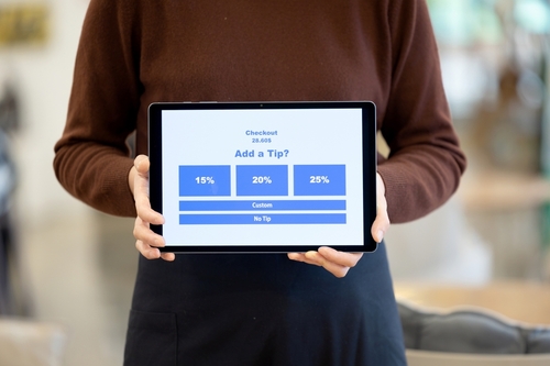 Employee holding a tablet on a tip payment screen.