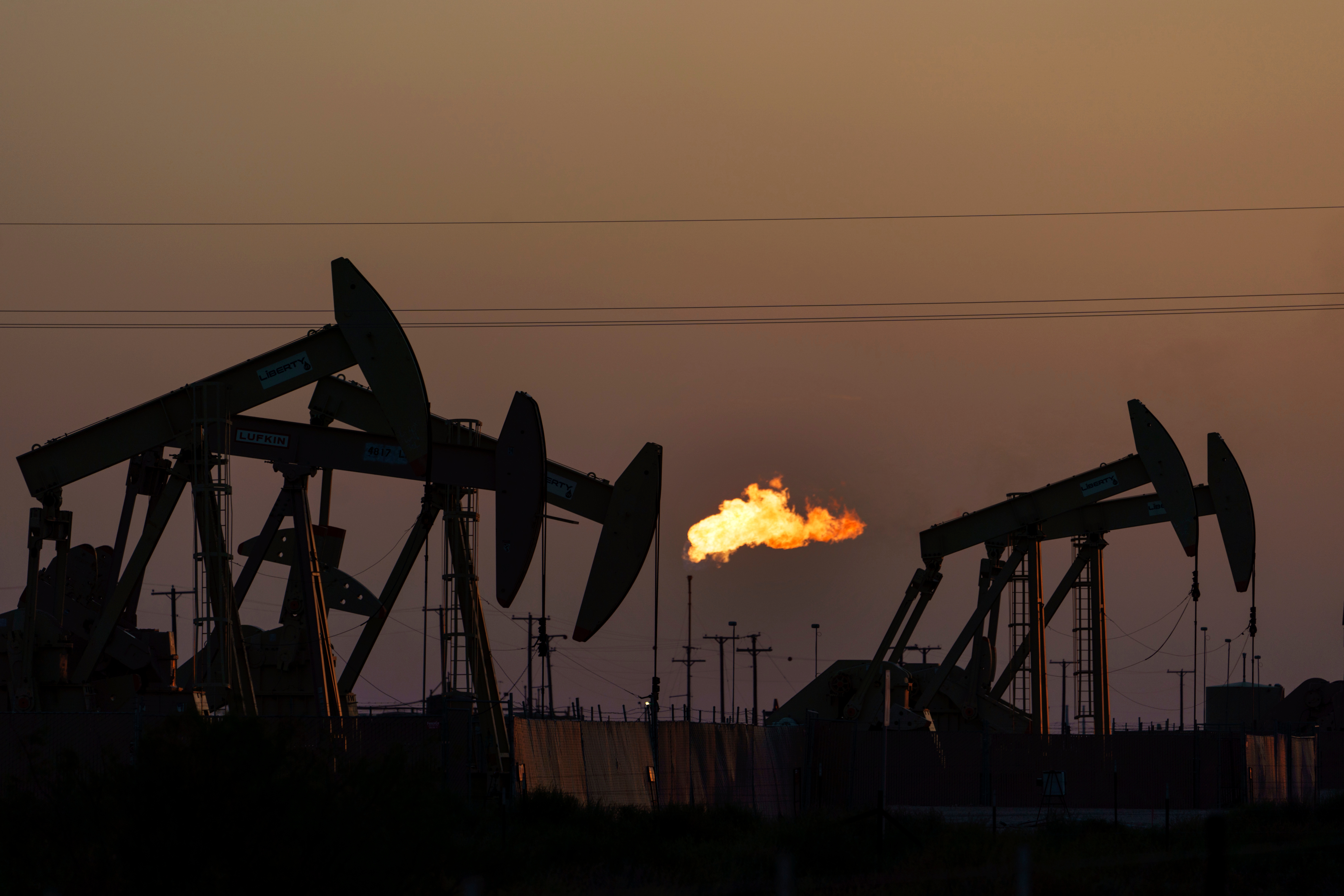 FILE - A flare burns off methane and other hydrocarbons as oil pumpjacks operate in the Permian Basin in Midland, Texas, on Oct. 12, 2021.