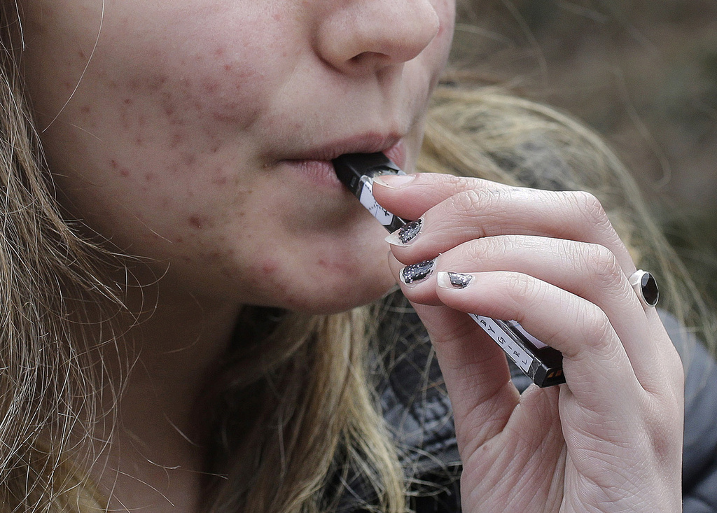 A high school student uses a vaping device near a school campus in Cambridge, Mass.