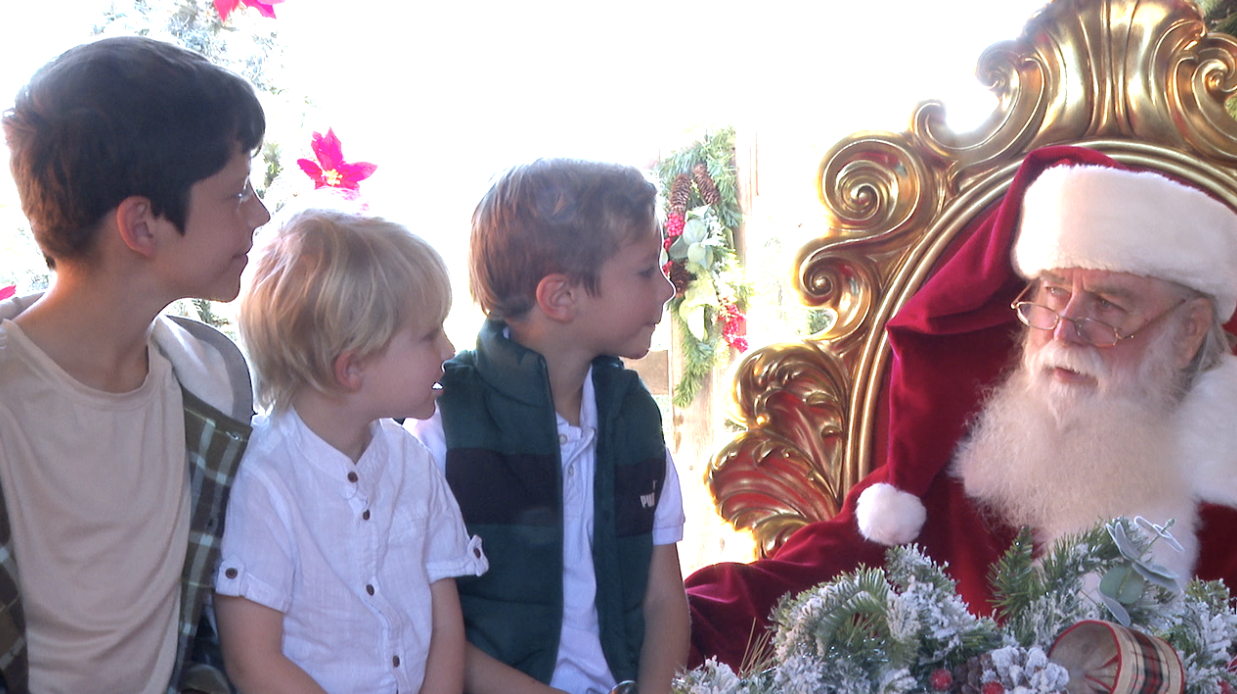 Santa with some eager kids, excited to take pictures with the holiday figure. 