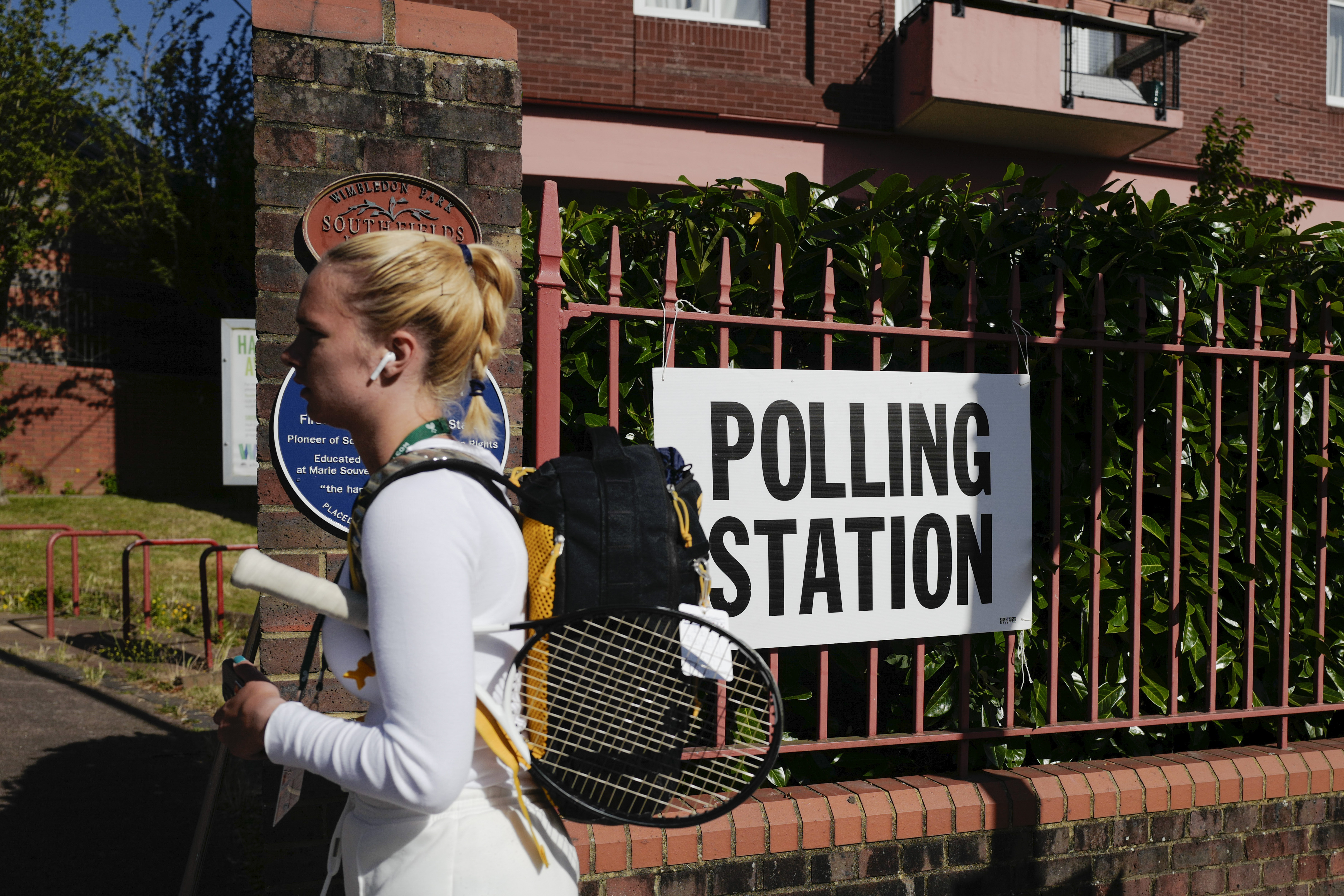 A woman walks past a temporary polling station near Wimbledon, London, Thursday, July 4, 2024.