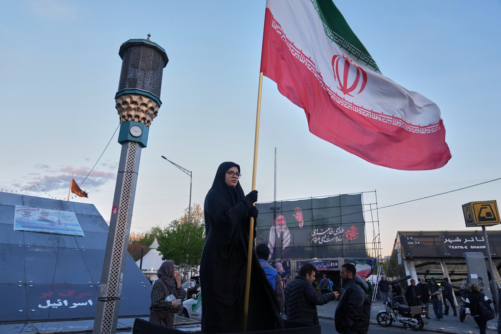 A woman holds an Iranian flag at an intersection in downtown Tehran, Iran, Monday, April 6, 2026. 