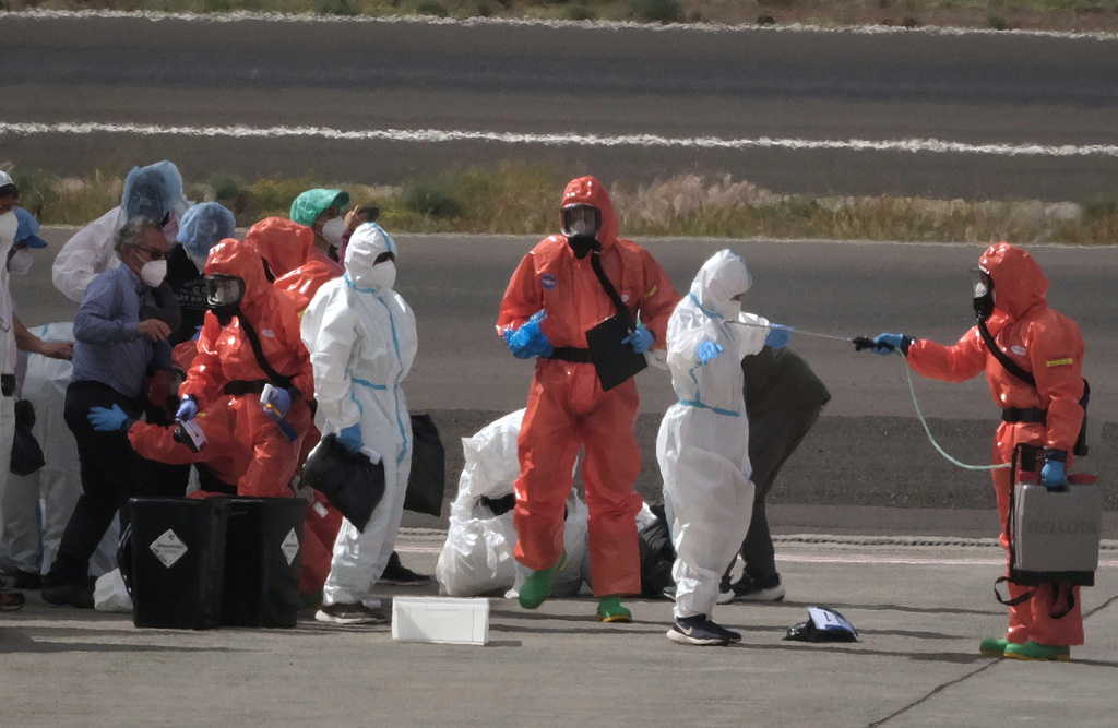Passengers are sprayed with disinfectant by Spanish government officials before boarding a plane after disembarking from the hantavirus-stricken cruise ship MV Hondius at Tenerife airport in the Canary Islands, Spain, Sunday, May 10, 2026.