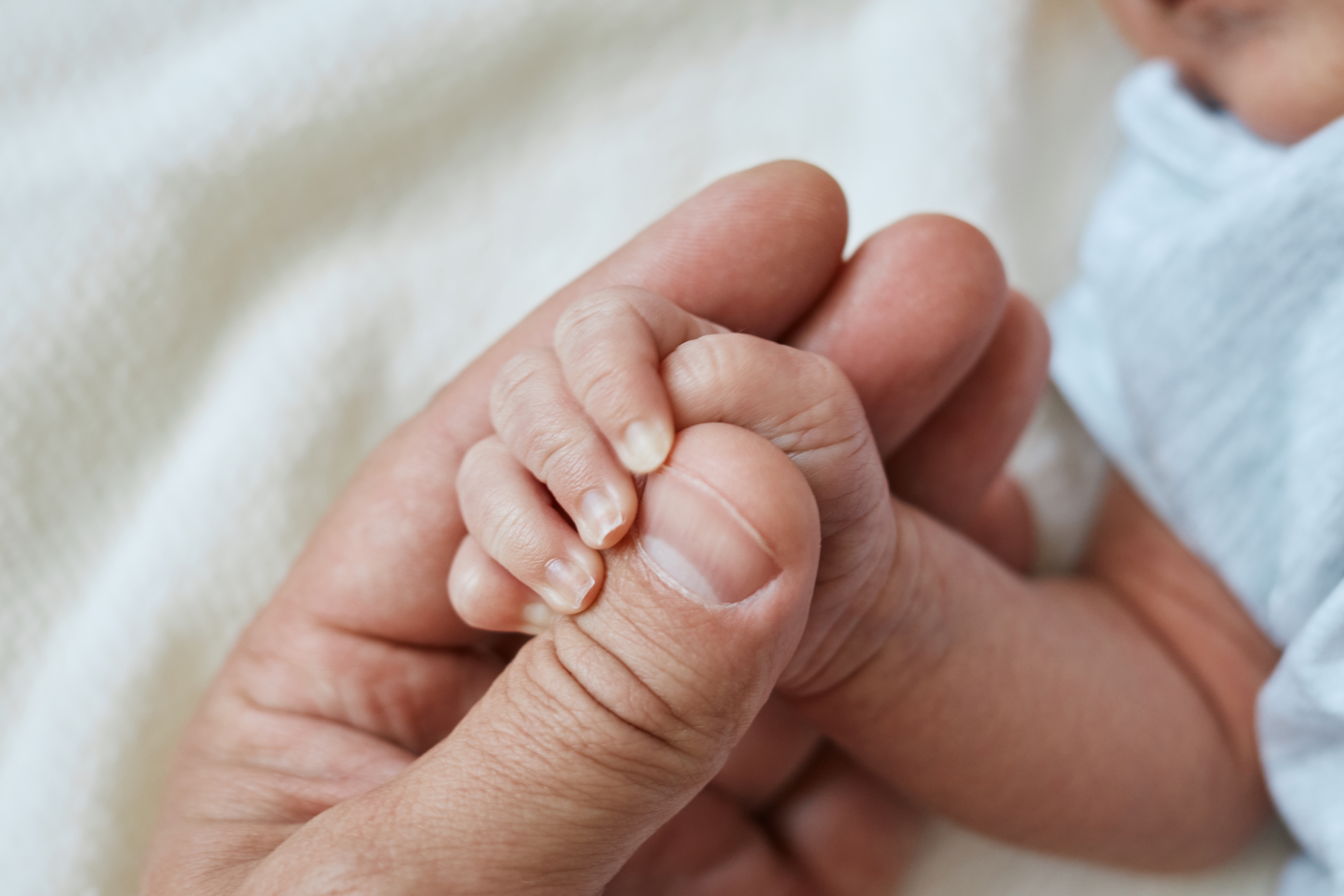 A person holds the hand of an infant. 