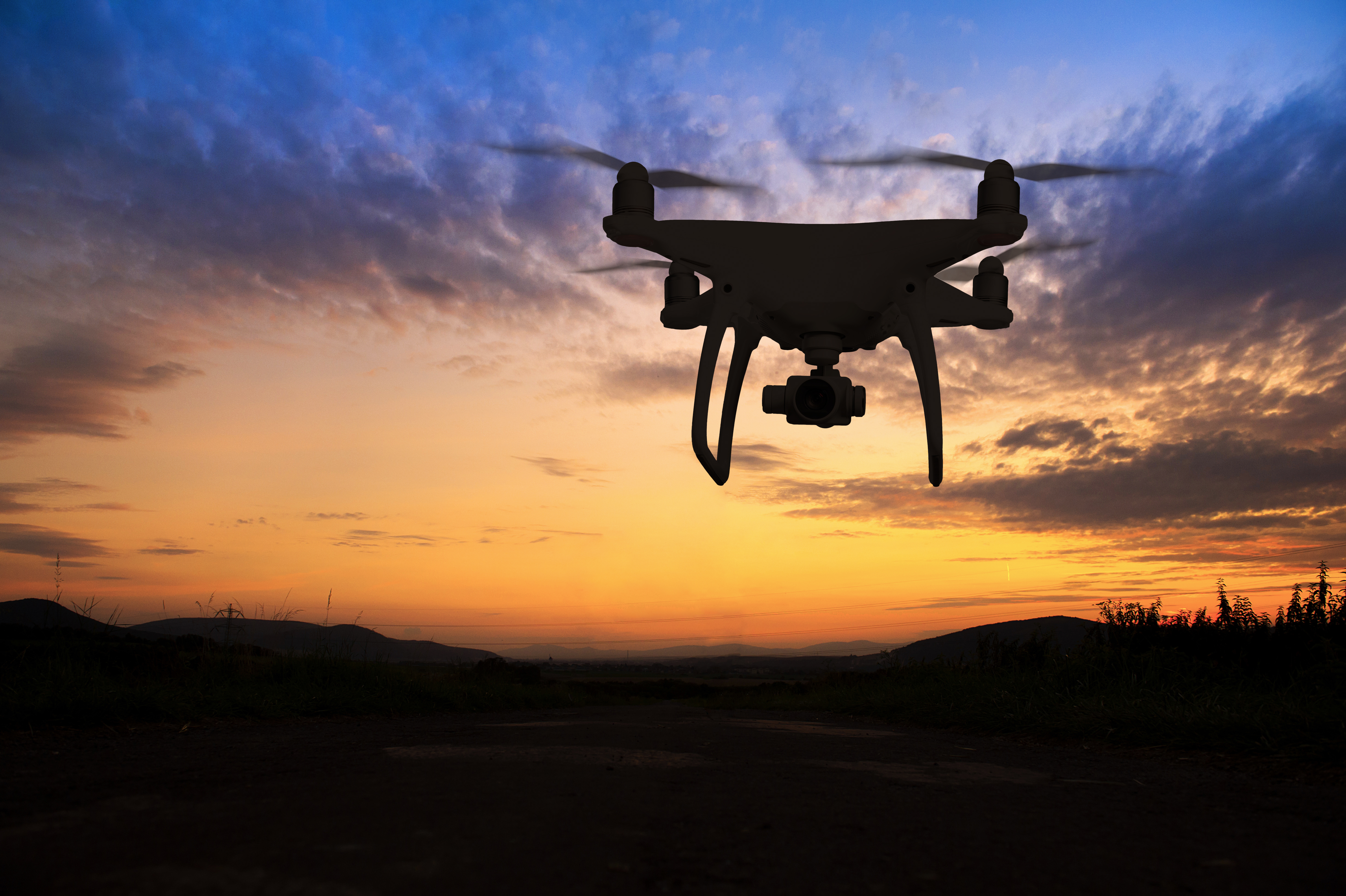 Silhouette of hovering drone taking pictures of nature at sunset