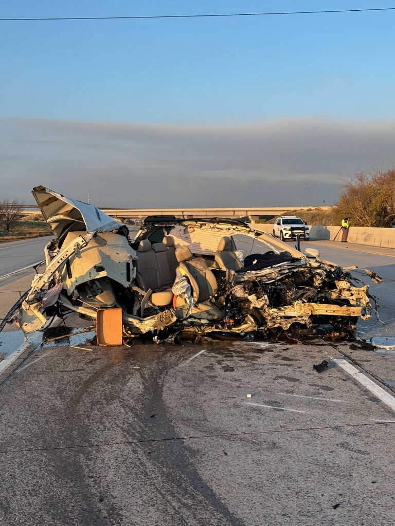 A photo from the scene released by Utah Highway Patrol. It's morning, and a vehicle sits on the road, utterly destroyed from the impact of the crash. The frame of the vehicle is a crumpled heap of metal, with the car's seats exposed to the elements.
