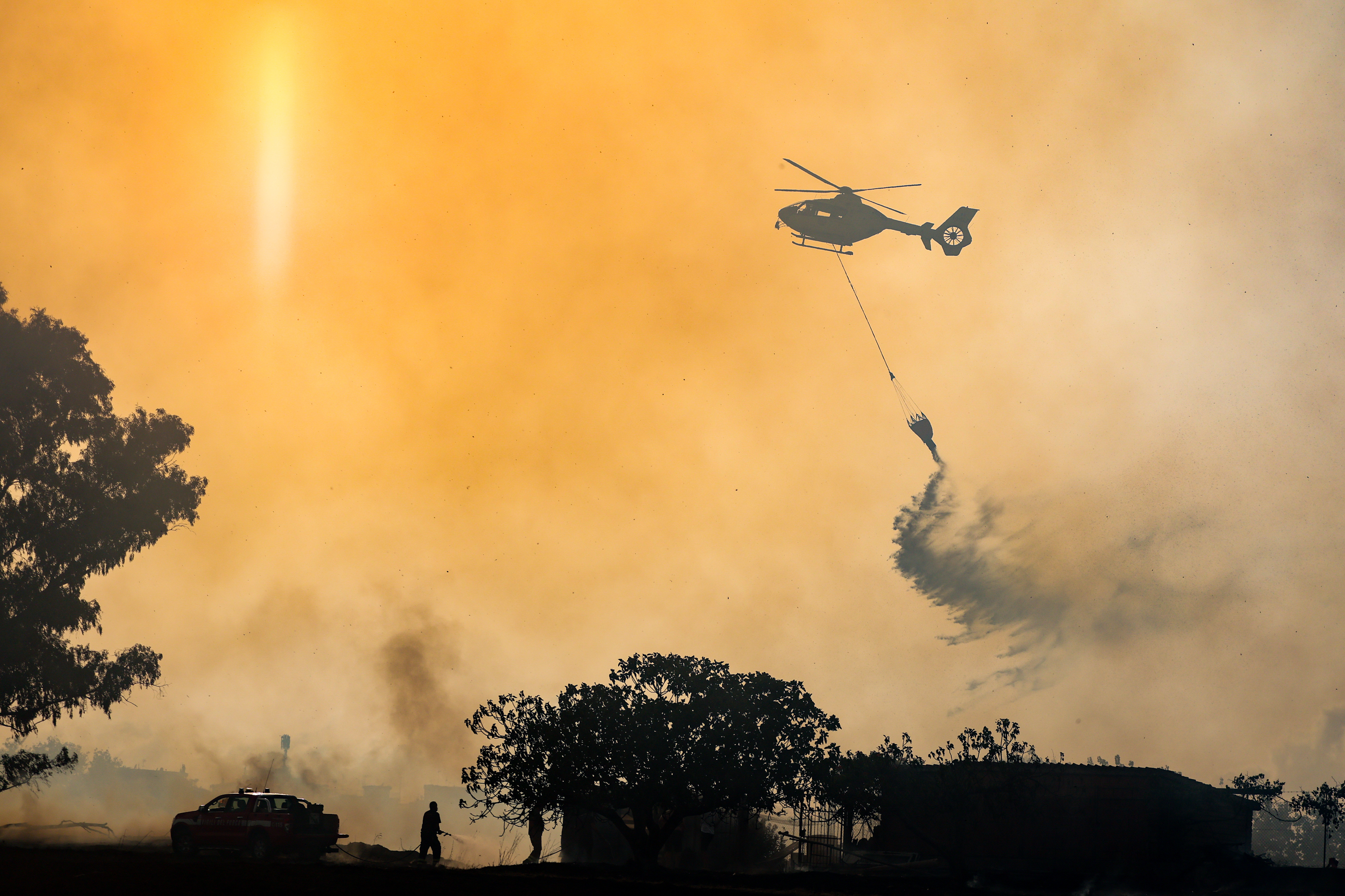 Firefighters use a helicopter to combat wildfires in Rome on Tuesday, July 21, 2026, after a fire broke out that, due to strong winds, quickly spread throughout the Acquafredda Nature Reserve.