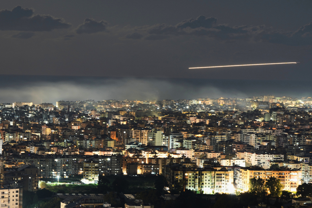 In this photo taken with a slow shutter speed, a Middle East Airlines plane flies over Beirut as smoke rises from Israeli airstrikes on Dahiyeh in Beirut's southern suburbs, early Monday, March 2, 2026. 
