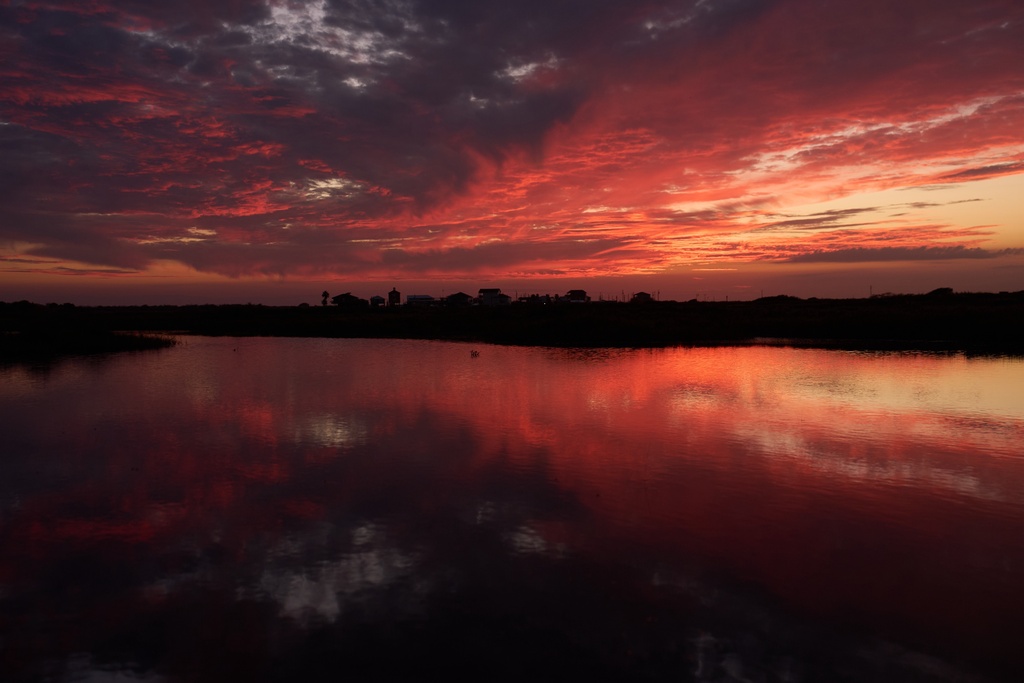 Clouds illuminated by the setting sun are reflected in water at the Wolfberry Whooping Crane Sanctuary, Friday, Dec. 12, 2025, near Seadrift, Texas. 