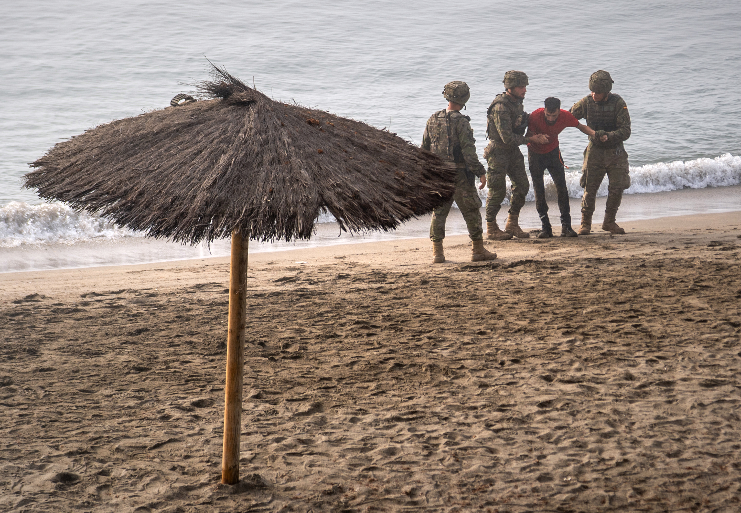 Spanish army soldiers assist a migrant who swam from Morocco to the Spanish enclave of Ceuta, Saturday, Aug. 1, 2026.