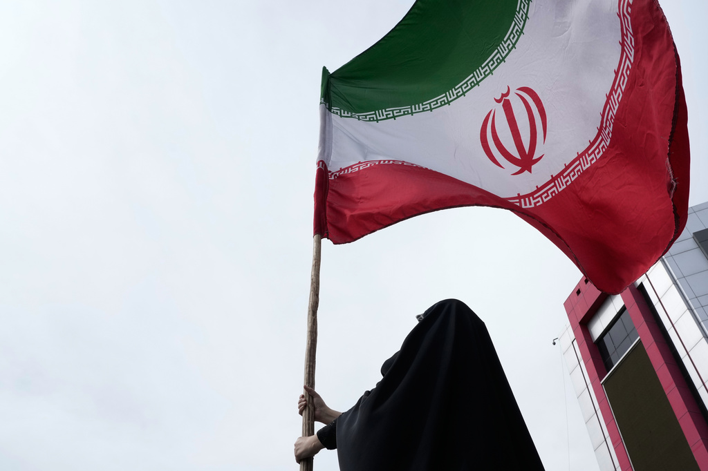 A woman holds an Iranian flag for a pro-government campaign in downtown Tehran, Iran, Saturday, April 25, 2026. 