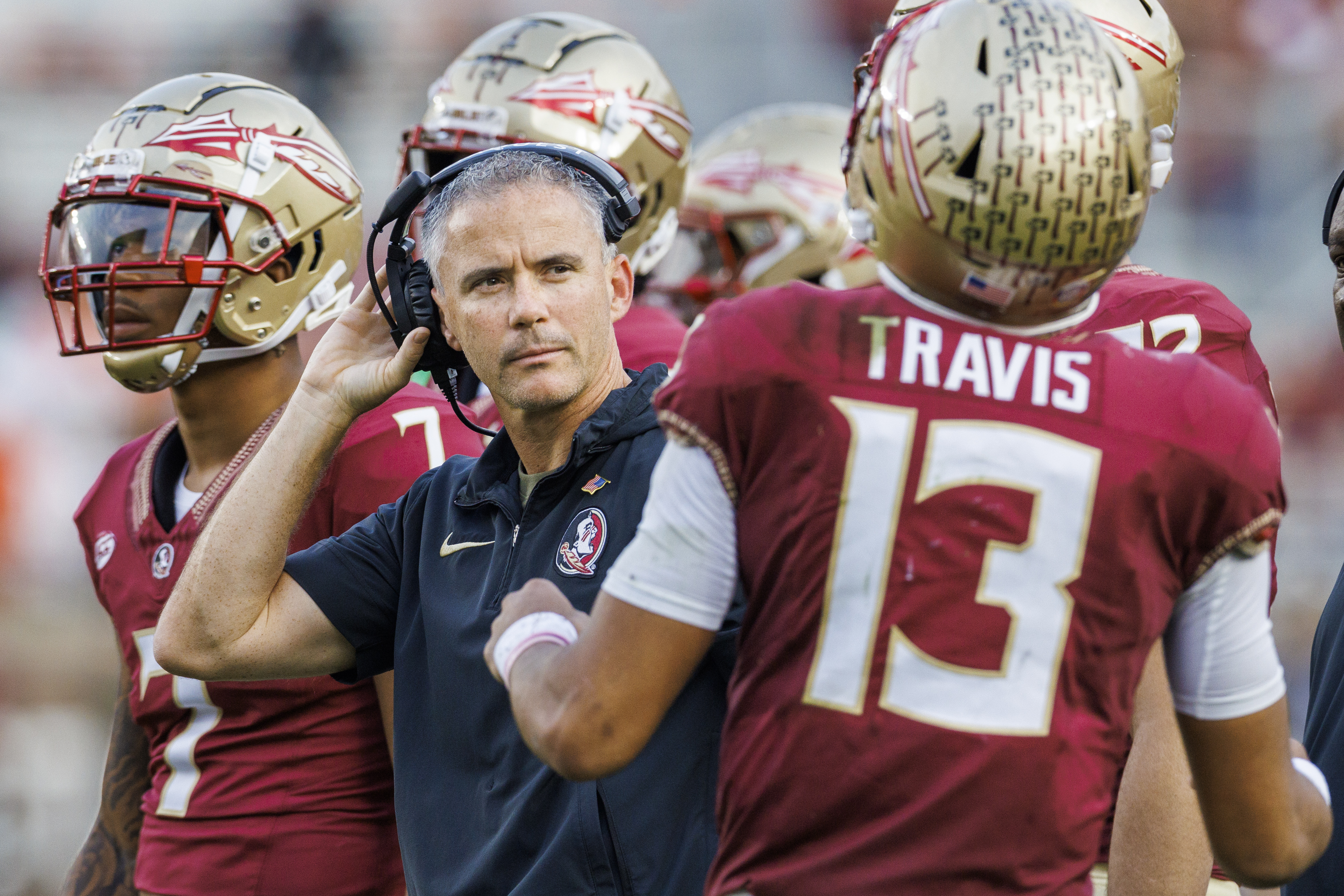 Florida State Seminoles head coach Mike Norvell listens to QB Jordan Travis on sideline vs. Miami Hurricanes, Nov. 11, 2023